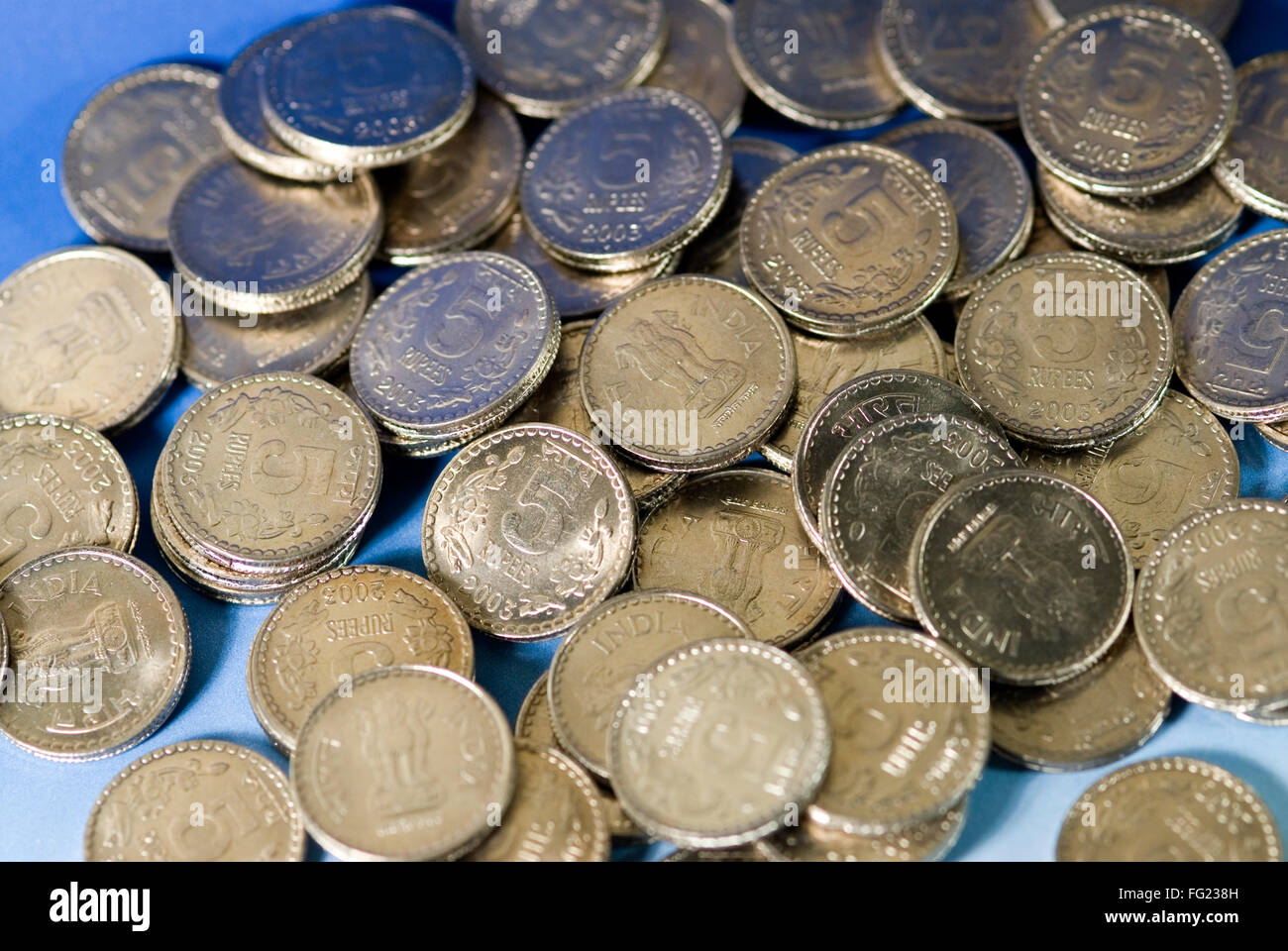 Konzept, verbreitete Wachstum indischen fünf Rupien Münzen auf blauem Hintergrund Stockfoto