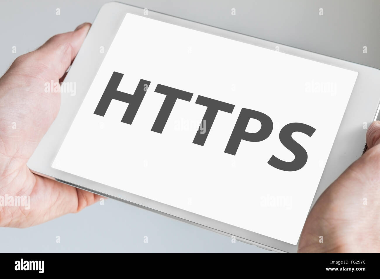 HTTPS Text auf Touch-Screen eines modernen Tablet-PCs. Hände halten mobiles Gerät im Internet surfen Stockfoto