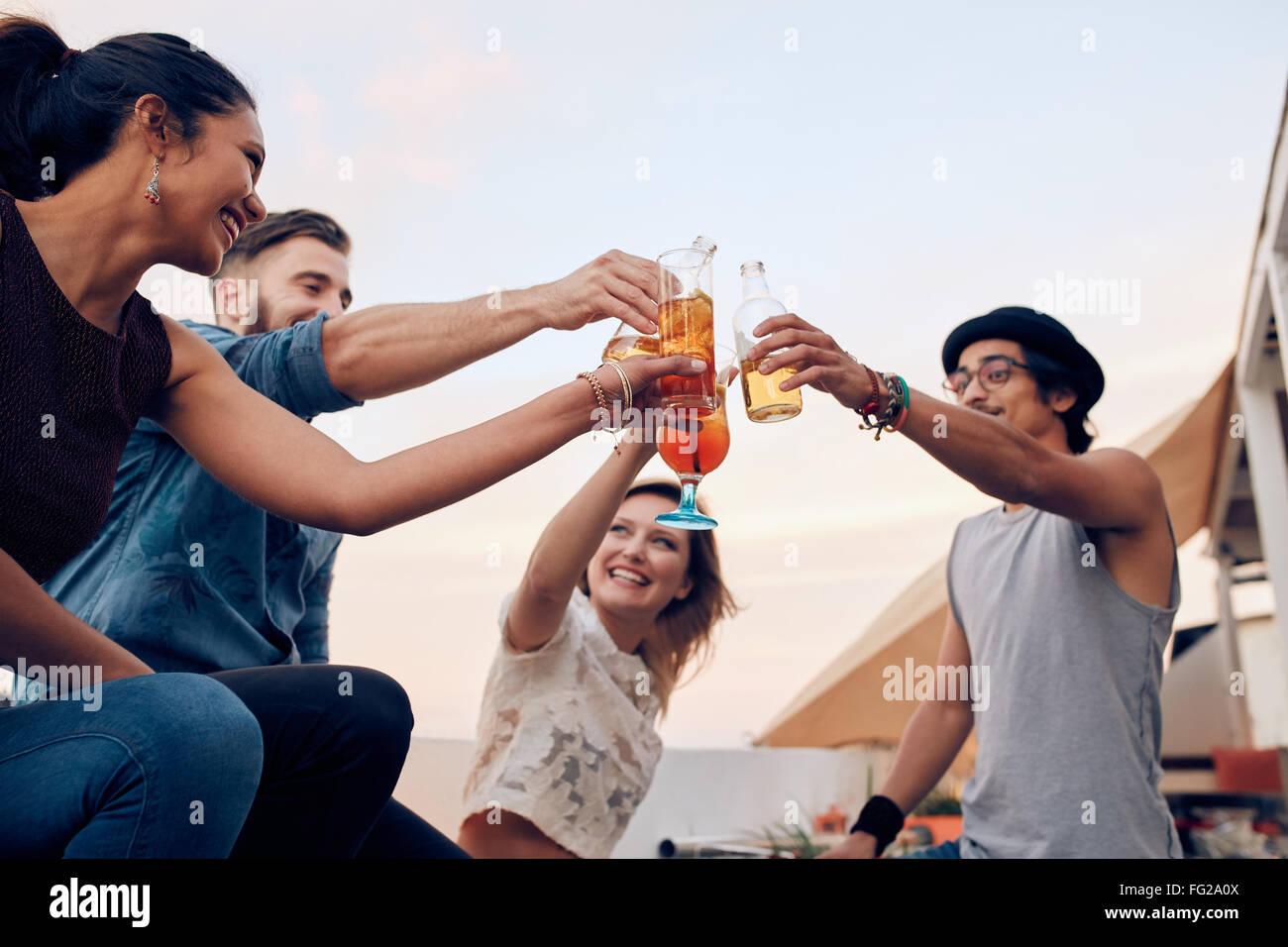 Porträt des Jugendlichen Toasten Cocktails während einer Party. Vier junge Freunde genießen in einer Partei. Junger Mann und Frau hängen Stockfoto