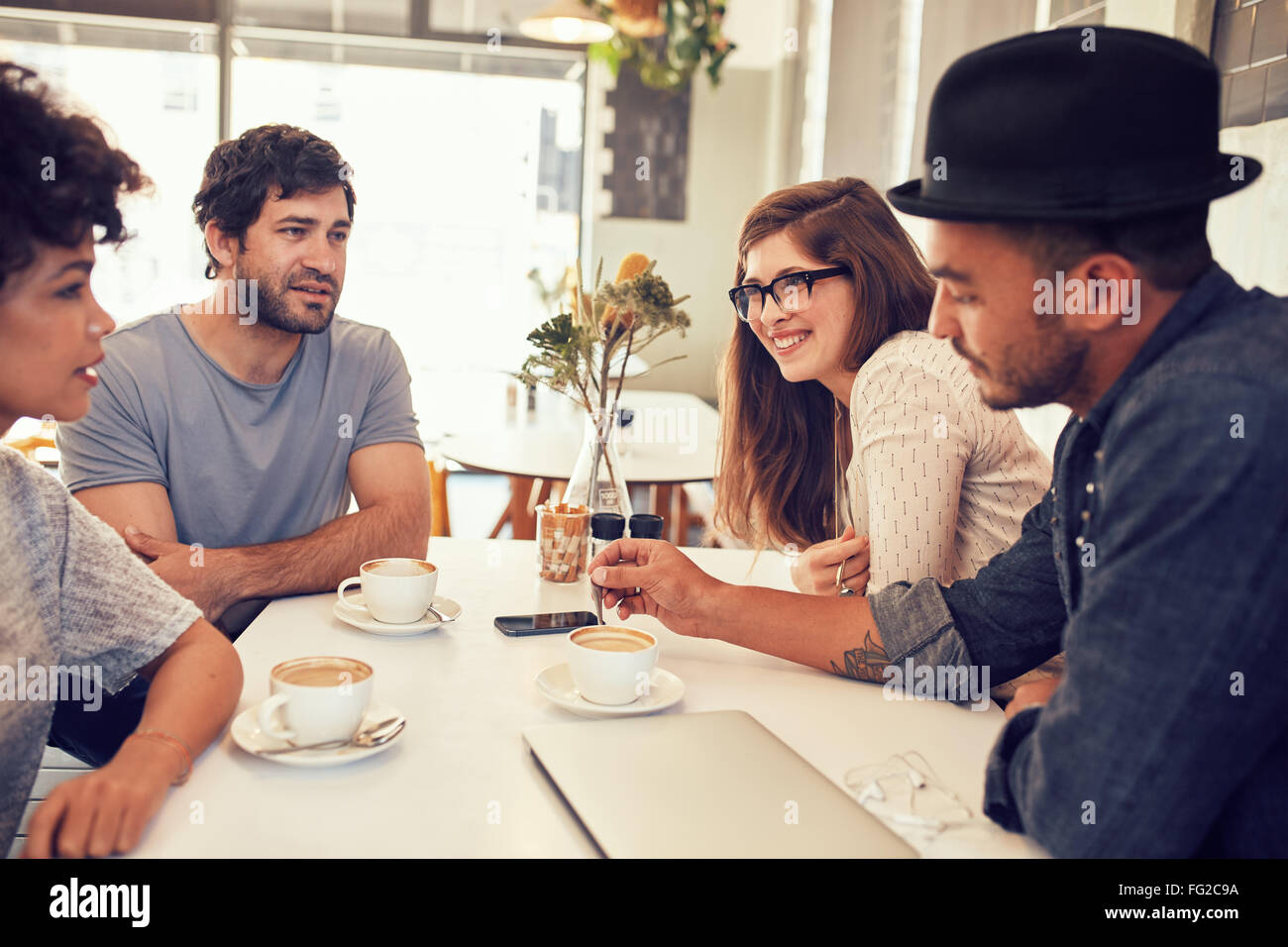 Gruppe junger Freunde sitzen und reden in einem Café. Junge Männer und Frauen haben einen Kaffee in einem Café und zu diskutieren. Stockfoto