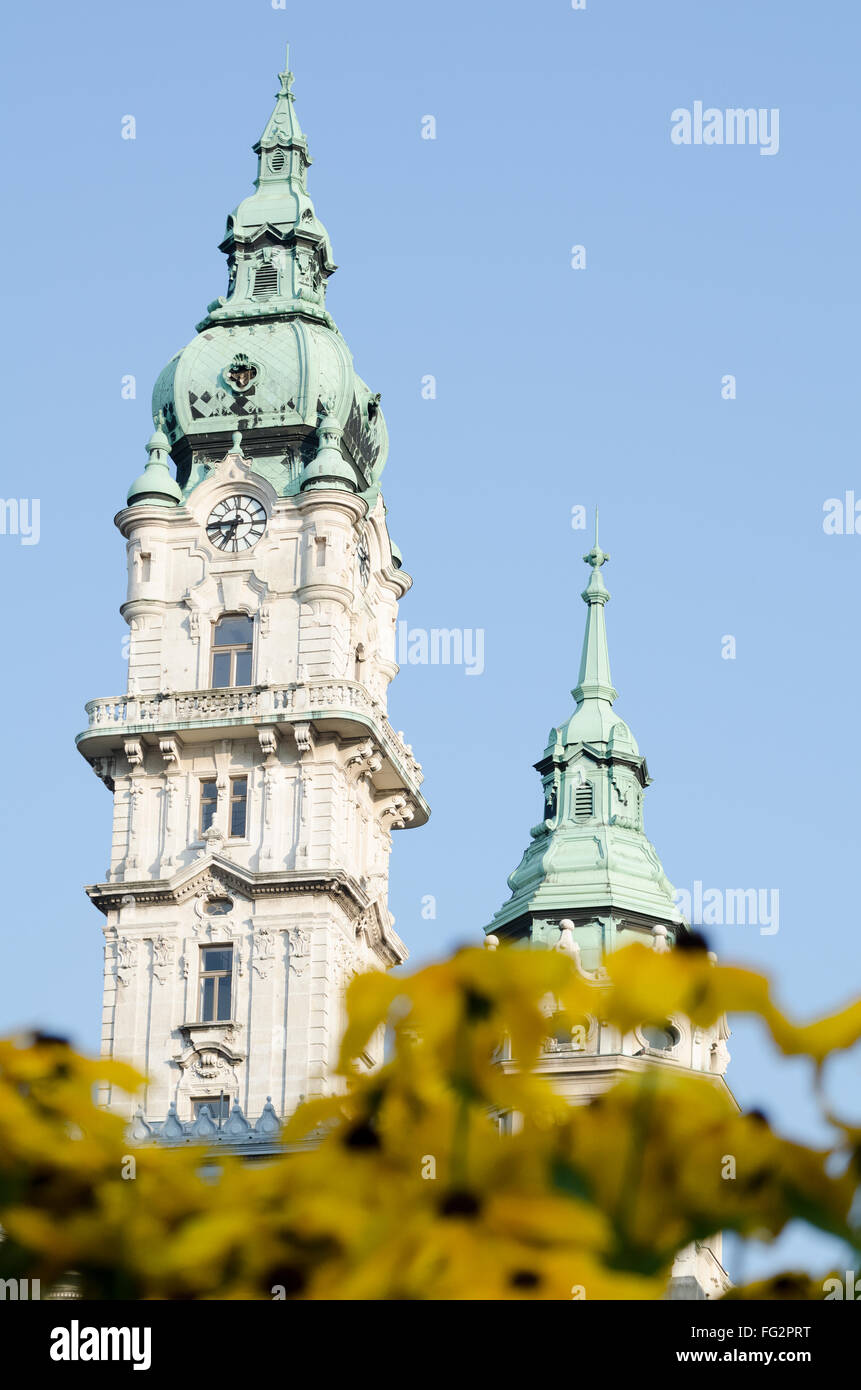 Gyor City Hall Türme mit gelben Blüten und klaren, blauen Himmel Stockfoto