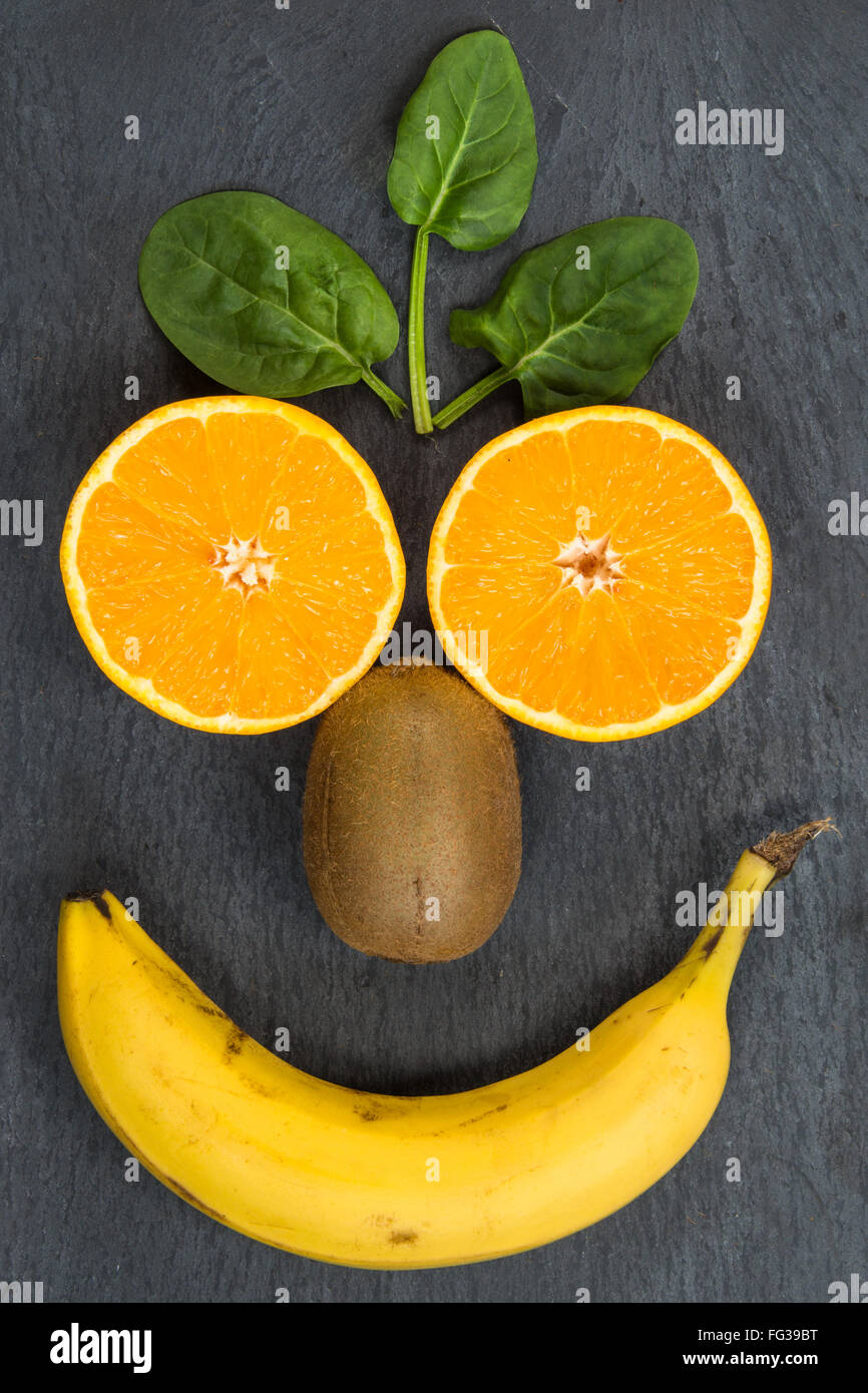 Früchte zu essen machen Sie Lächeln wie dieses glückliches Gesicht. Essen Sie Bio, bleiben Sie gesund zu. Essen-Platte mit Früchten auf einem dunklen Hintergrund. Stockfoto