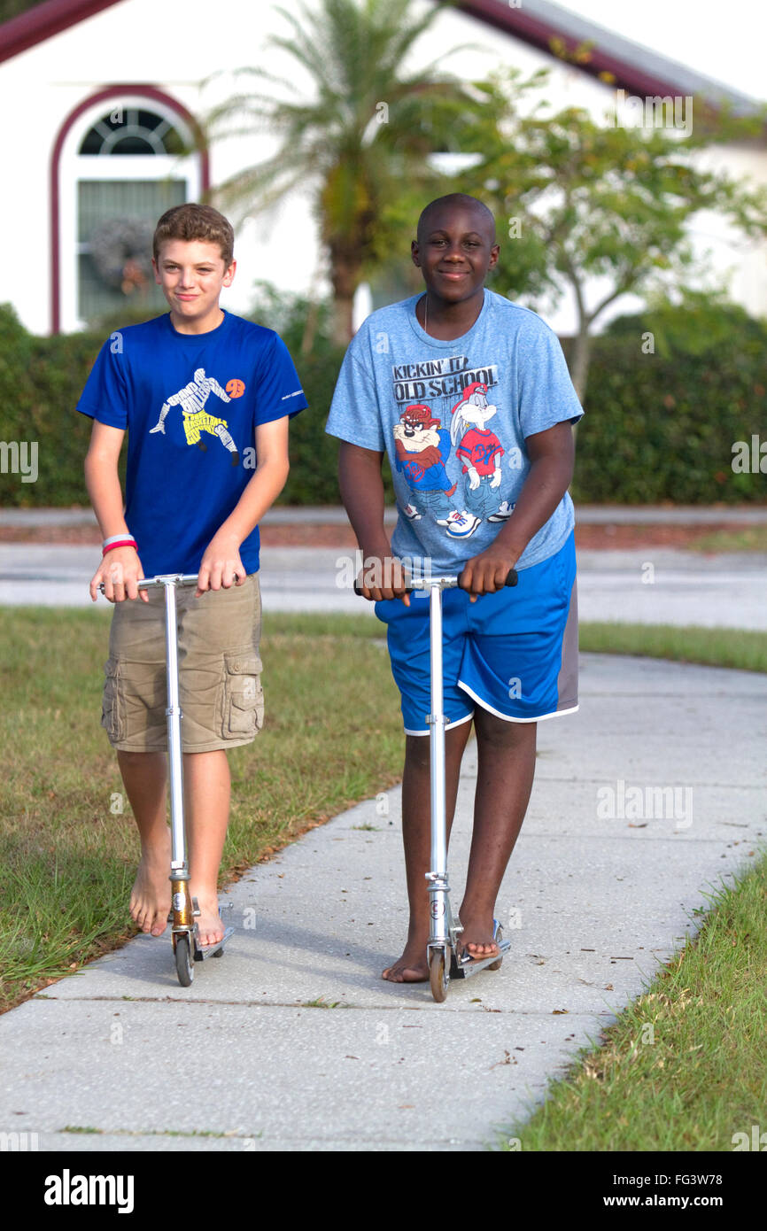 Zwei 11-jährige Jungen fahren Roller in Florida, USA. Stockfoto