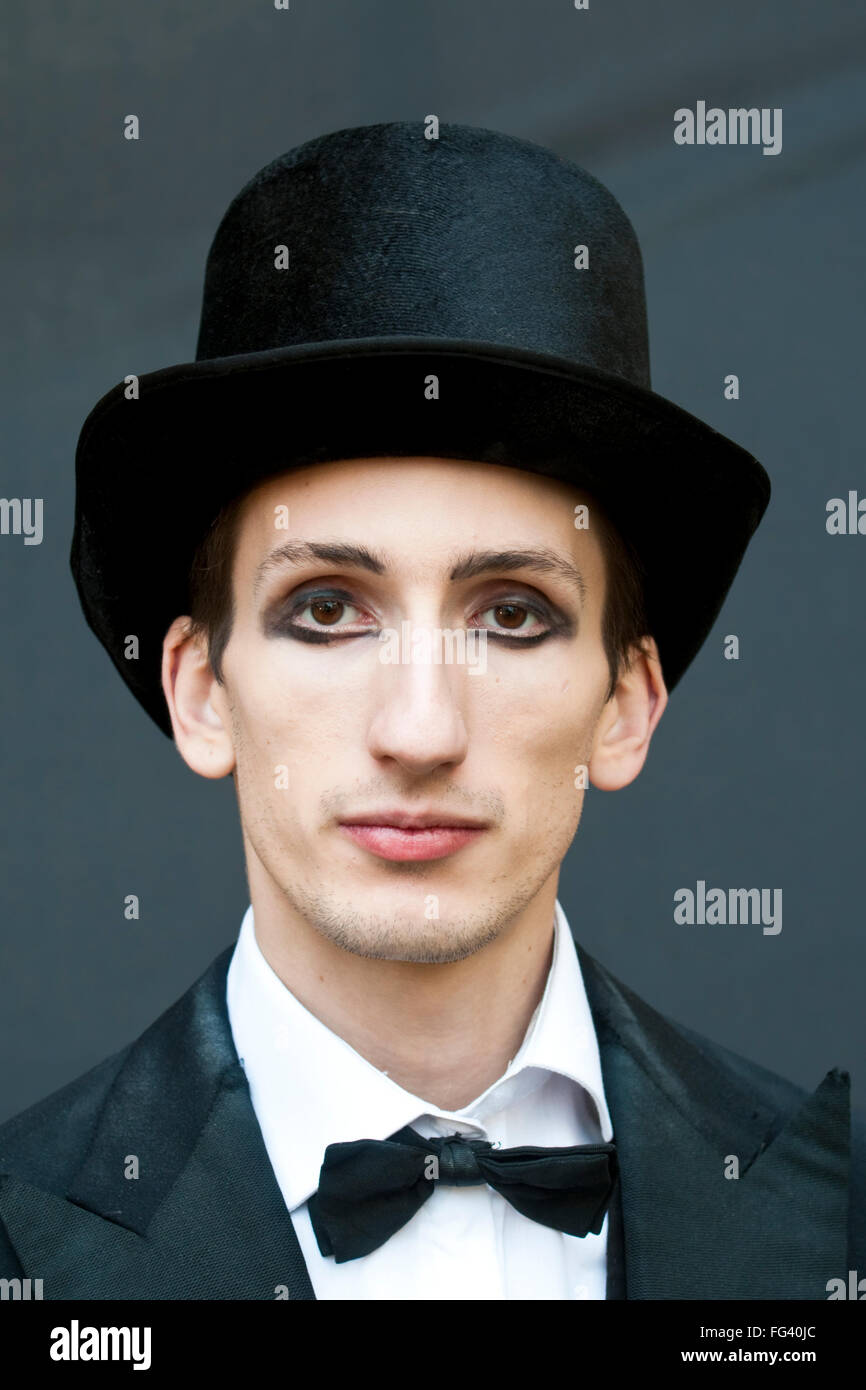 Ein Mann mit schweren Augen Make-up, gekleidet wie ein Zirkusdirektor in einem Zylinder und Fliege Stockfoto