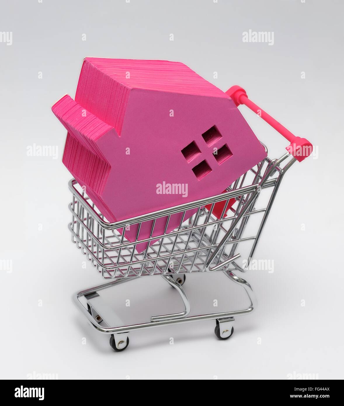 Rosa Papierblock in Form eines Hauses in einem Supermarkteinkaufswagen Stockfoto