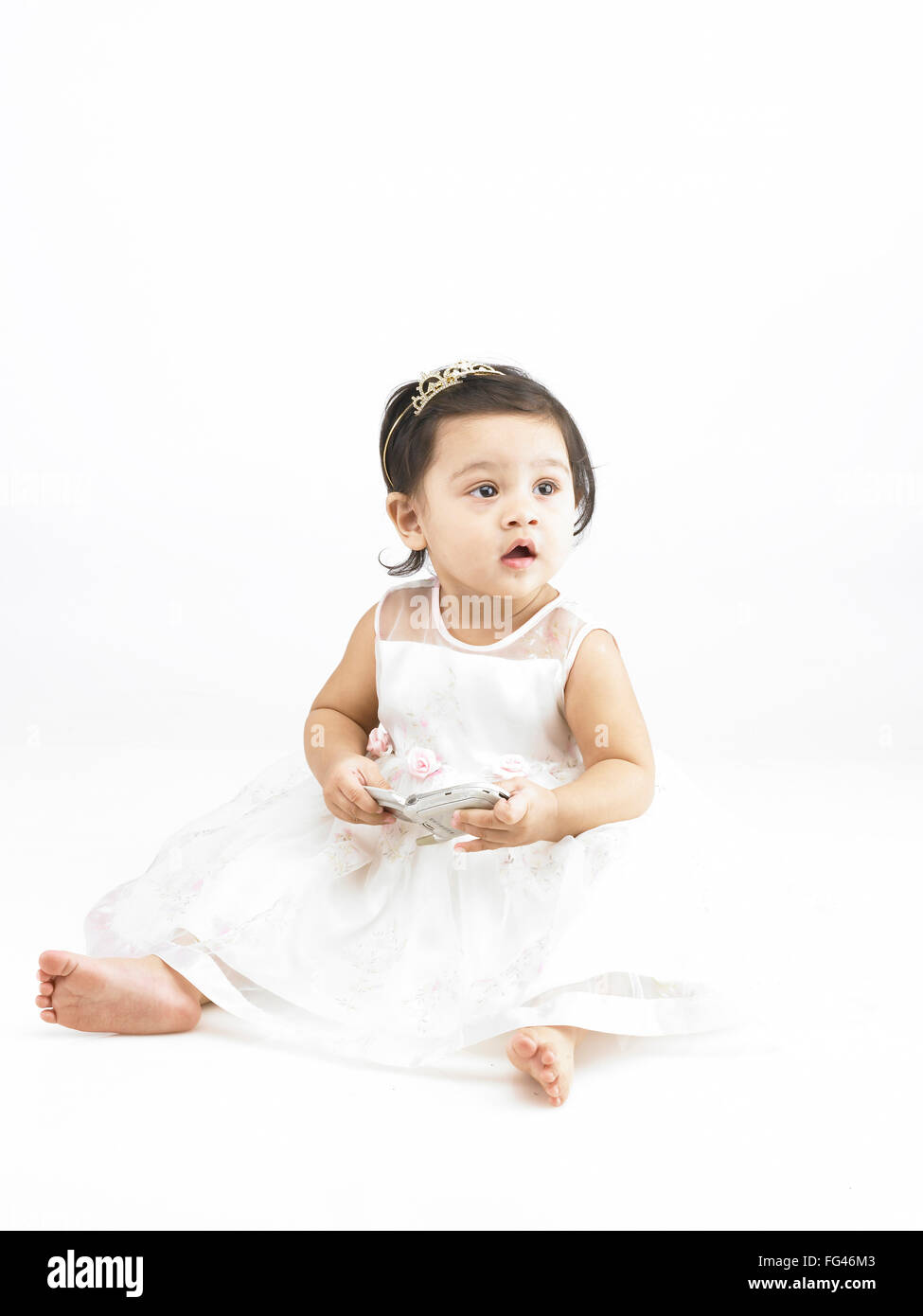 Freudige indischen Babymädchen tragen weiße Kleid hält mobile Herr #702O Stockfoto