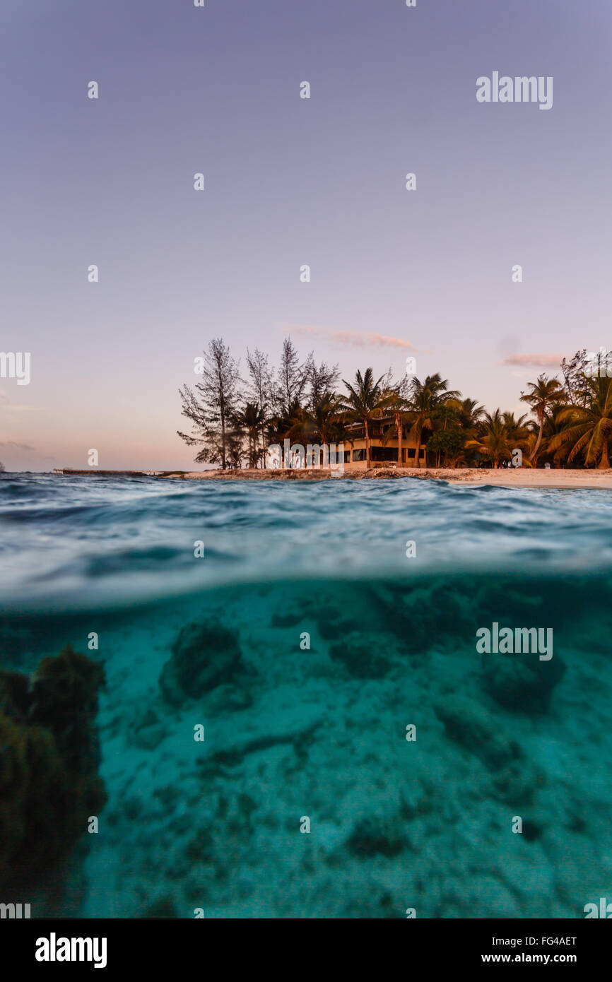 Haus am Strand und blau tropische Gewässern gesehen vom Gewässerrand halb unter und halb über der Wasserlinie Stockfoto