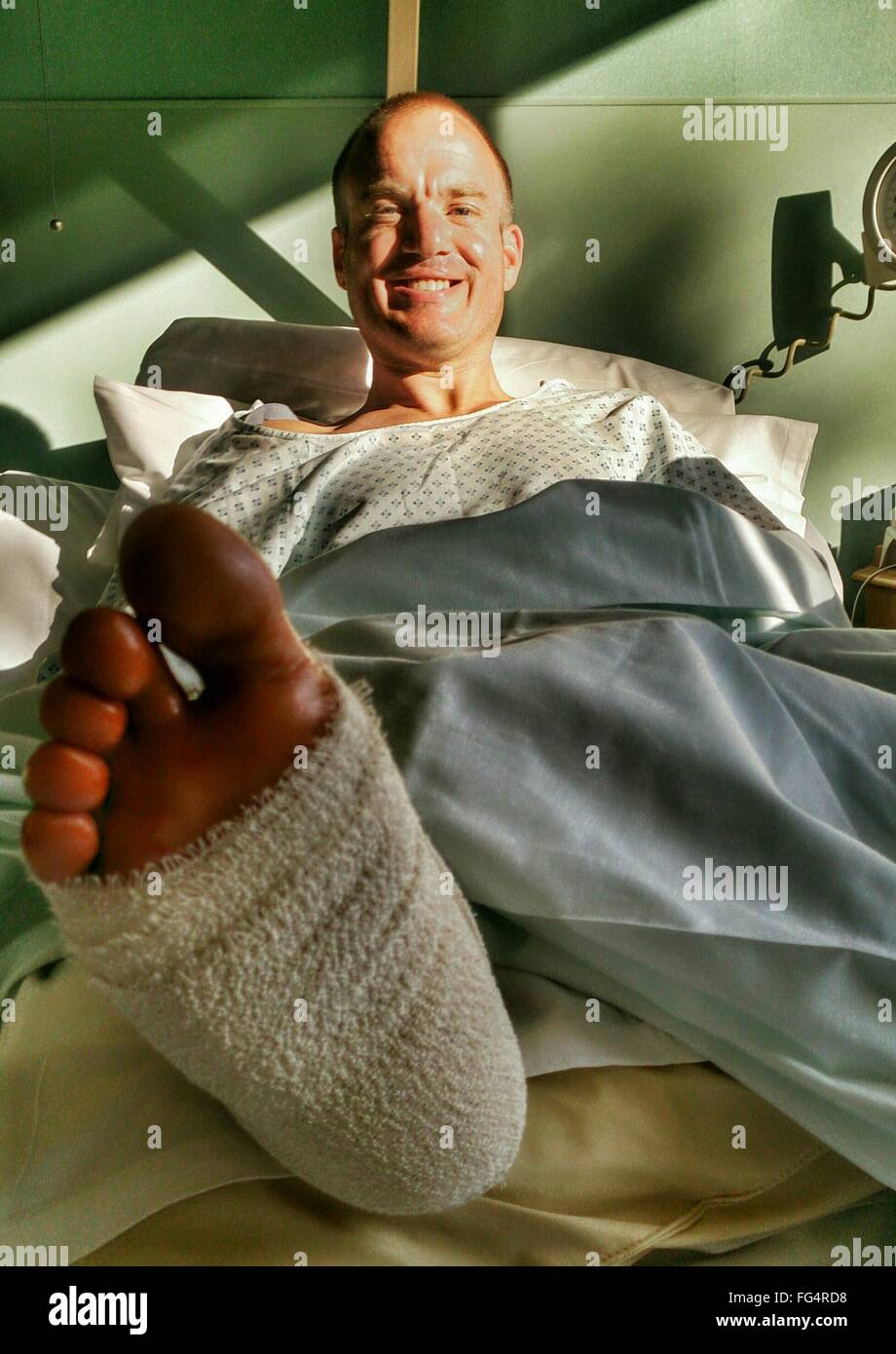 Porträt von glücklich Mitte erwachsenen Mann mit gebrochenem Bein erholt sich im Krankenhaus Stockfoto