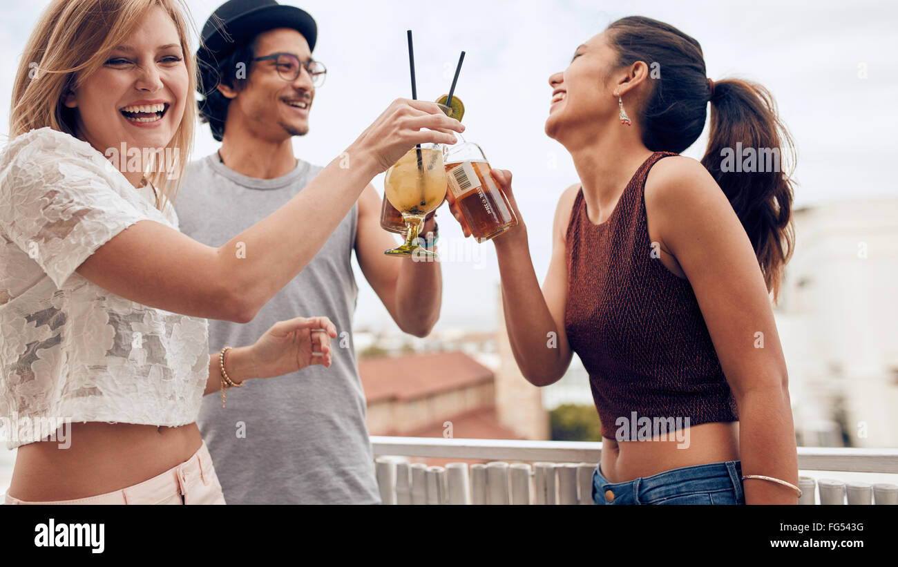 Porträt der jungen Frau, die mit ihren Freunden während einer Party cocktail toasten. Drei junge Freunde genießen in einer Partei. Junger Mann eine Stockfoto