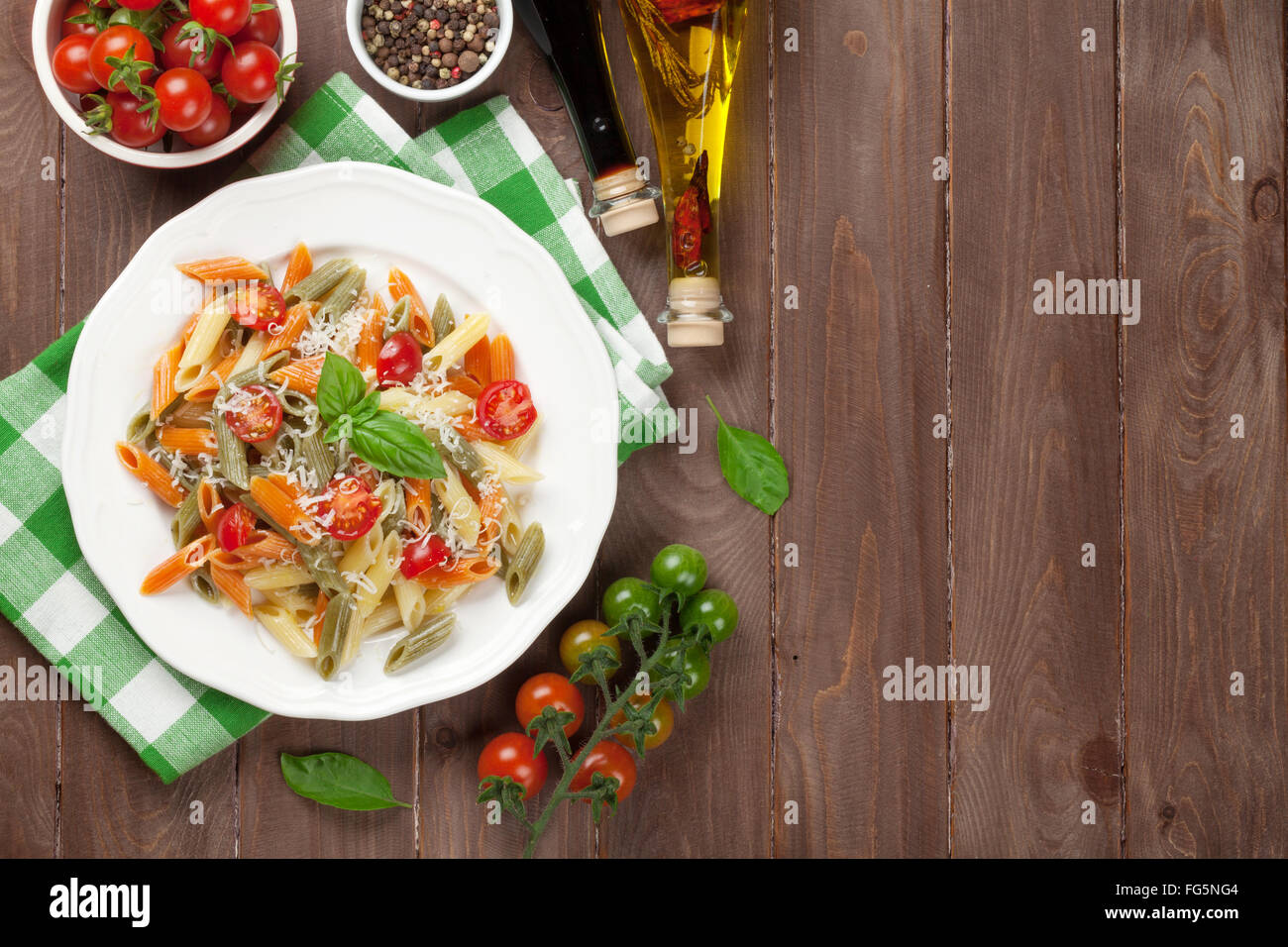 Bunte Penne-Nudeln mit Tomaten und Basilikum auf Holztisch. Draufsicht ...