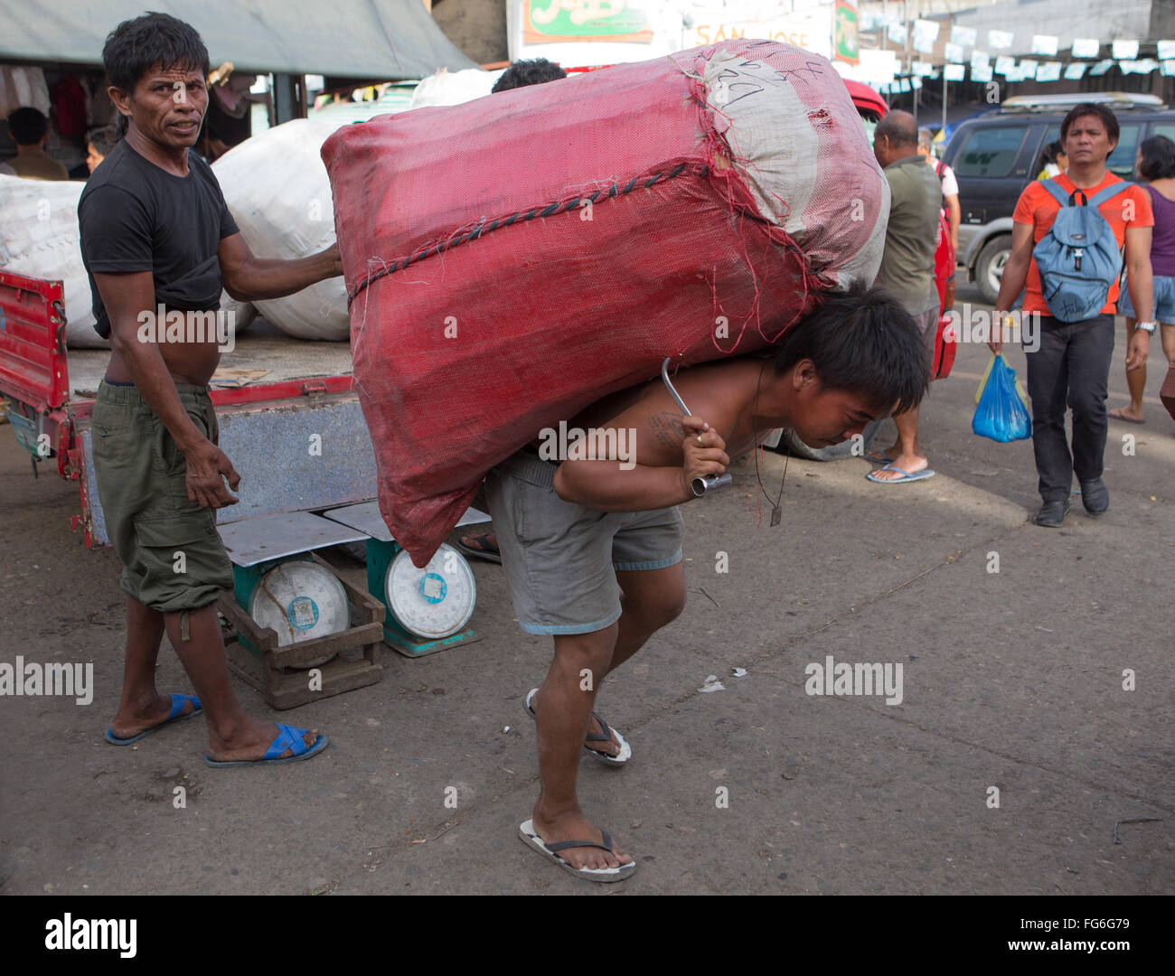 Eine schwere Last getragen von einem philippinischen Mann innerhalb der CO2-Markt befindet sich im Zentrum von Cebu City, Philippinen Stockfoto