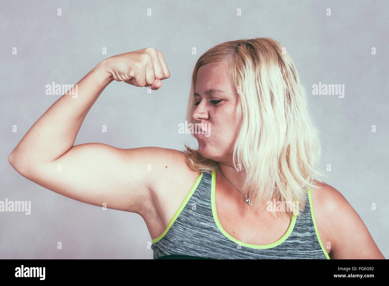 Starke muskuläre selbstbewusste Frau ihre Muskeln. Junge blonde sportlich weiblich mit Arm und Bizeps. Stockfoto