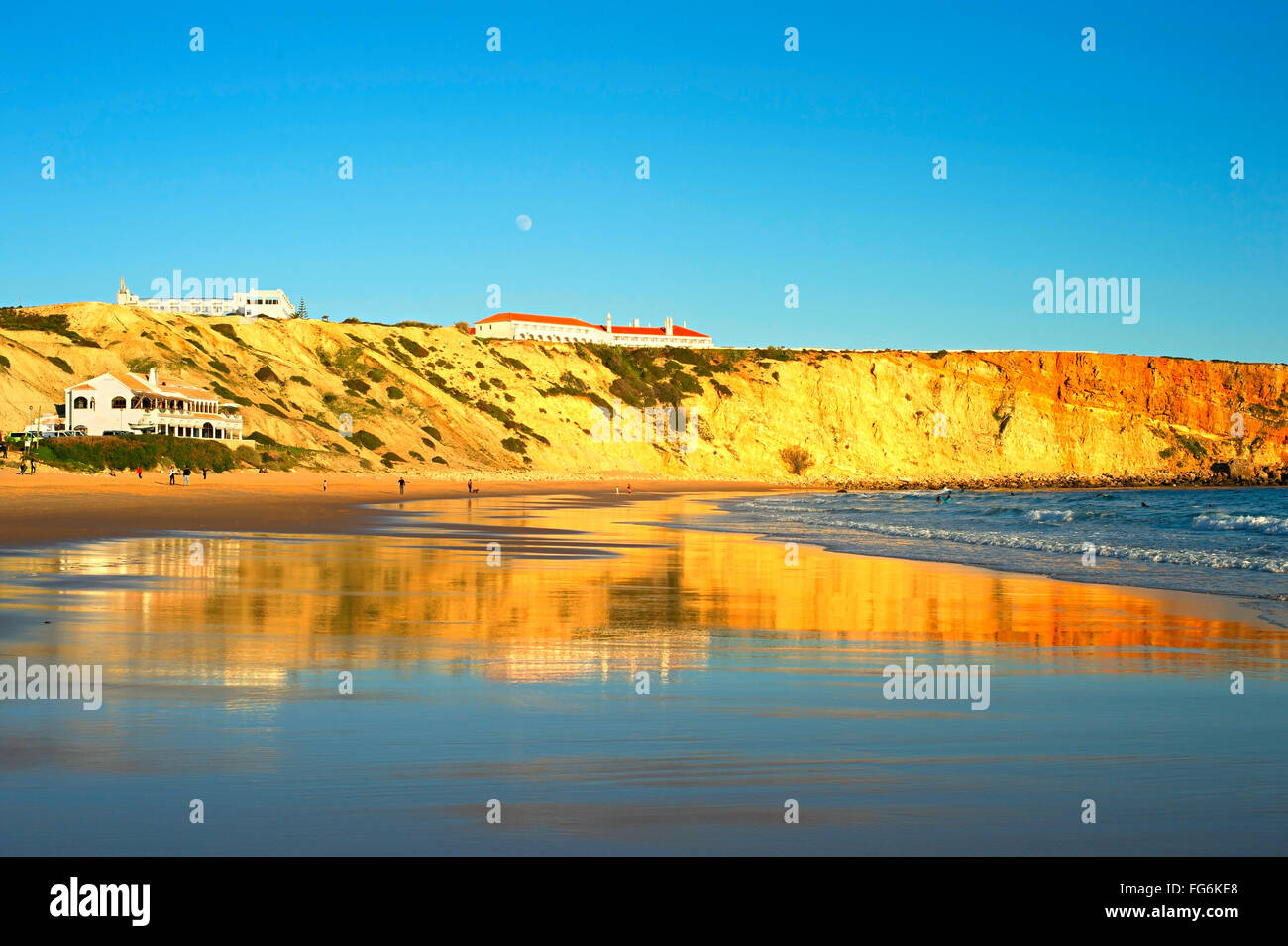 Menschen am Ocean Beach bei Sonnenuntergang. Vollmond am Himmel.  Portugal Stockfoto