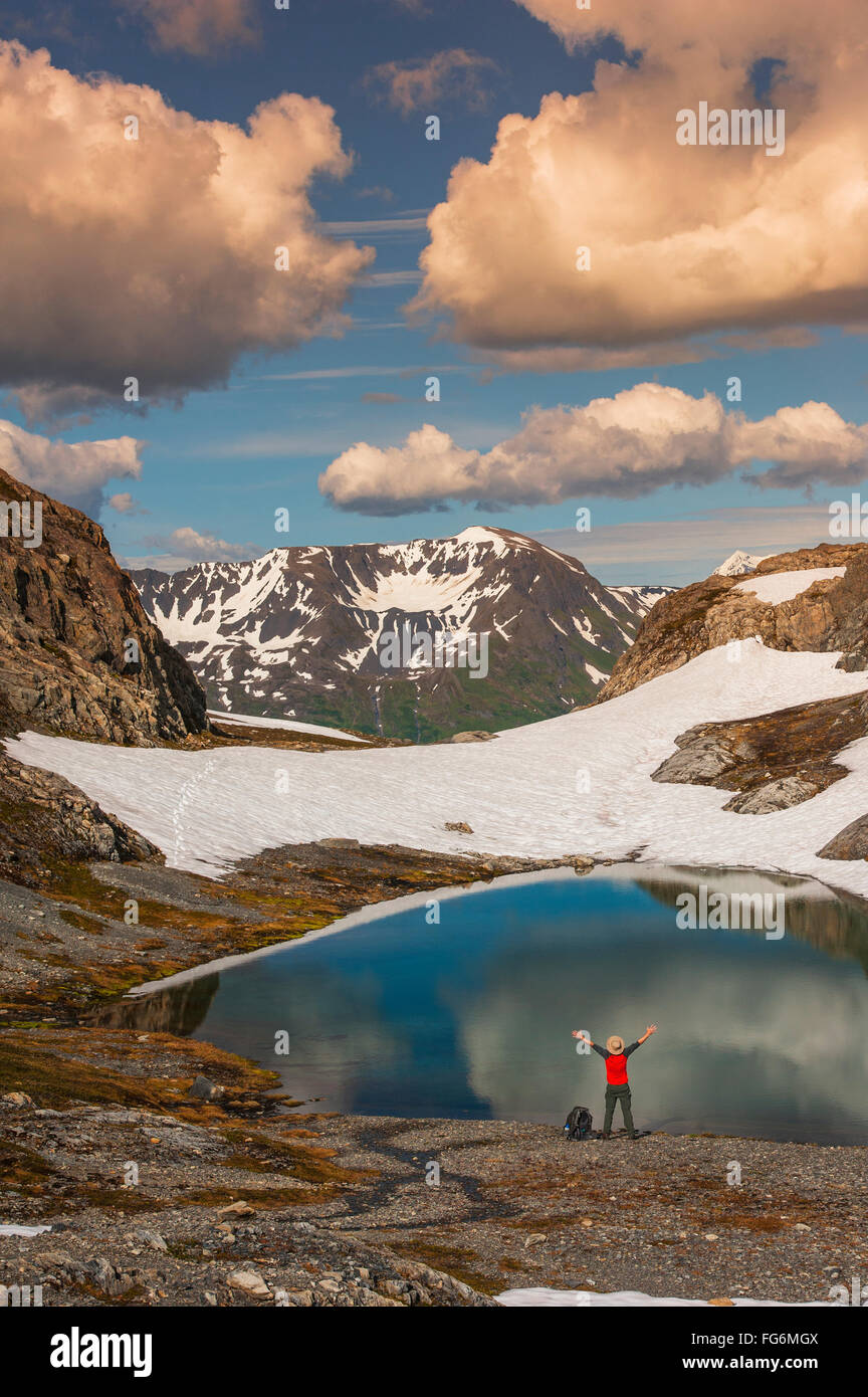 Ein Mann, der an Einem See mit ausgestreckten Armen in der Nähe des Harding Icefield Trail mit den Chugach Mountains im Hintergrund steht, Kenai Fjords Nati... Stockfoto