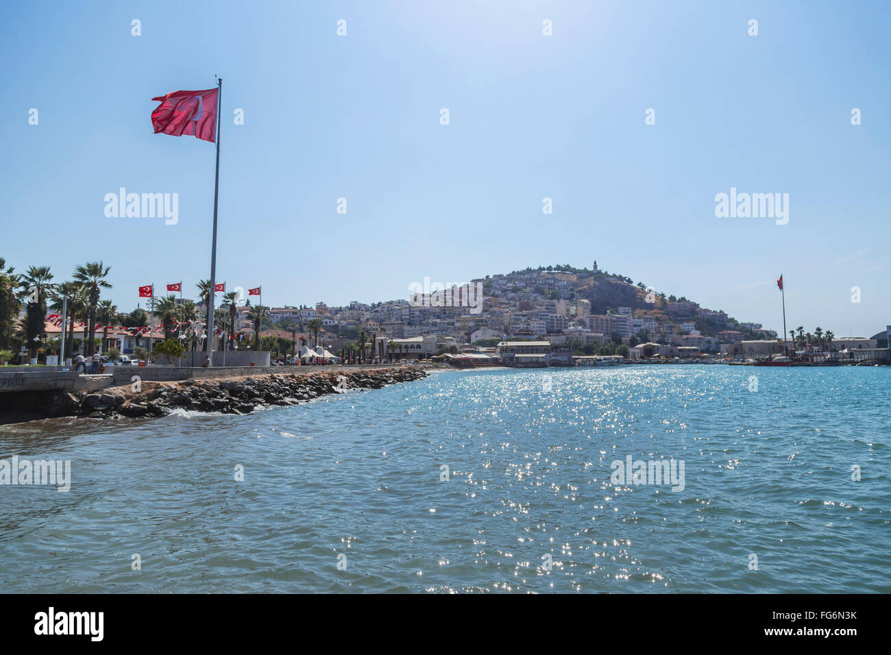 Die türkische Flagge fliegt am blauen Himmel an einem sonnigen Tag neben dem Mittelmeer; Kusadasi, Izmir, Türkei Stockfoto