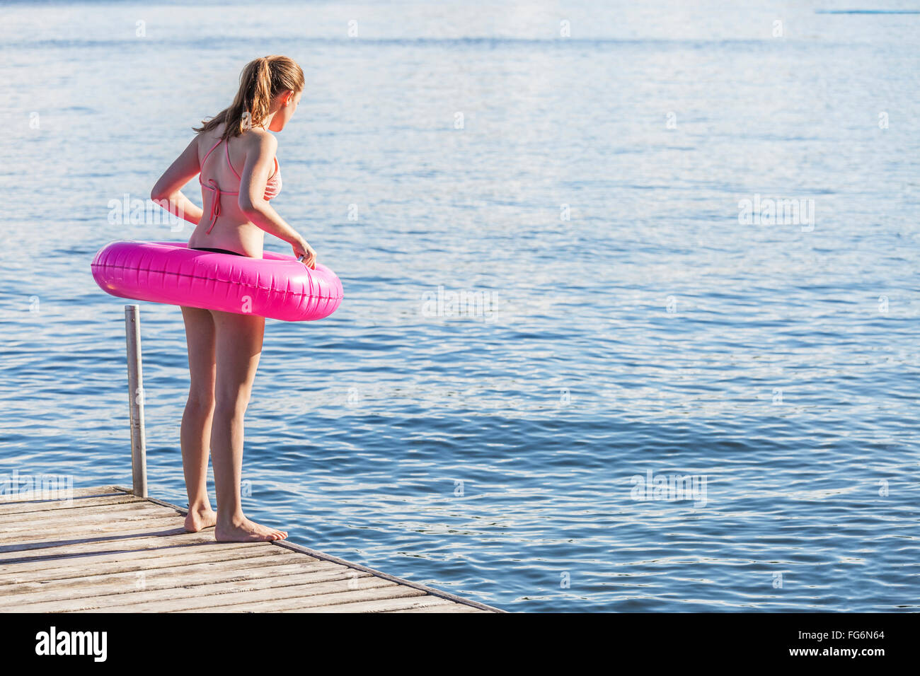Mädchen stehen am Rand des Hafenbeckens von Balsam Lake tragen aufblasbaren Ring; Ontario, Kanada Stockfoto