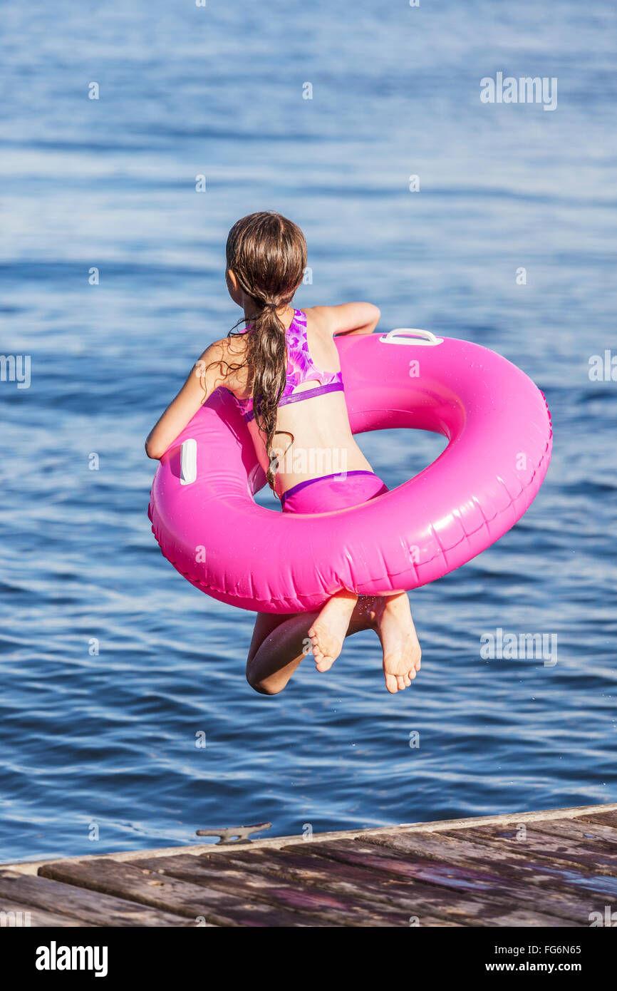 Mädchen springen weg von einem Dock von Balsam Lake tragen aufblasbaren Ring; Ontario, Kanada Stockfoto