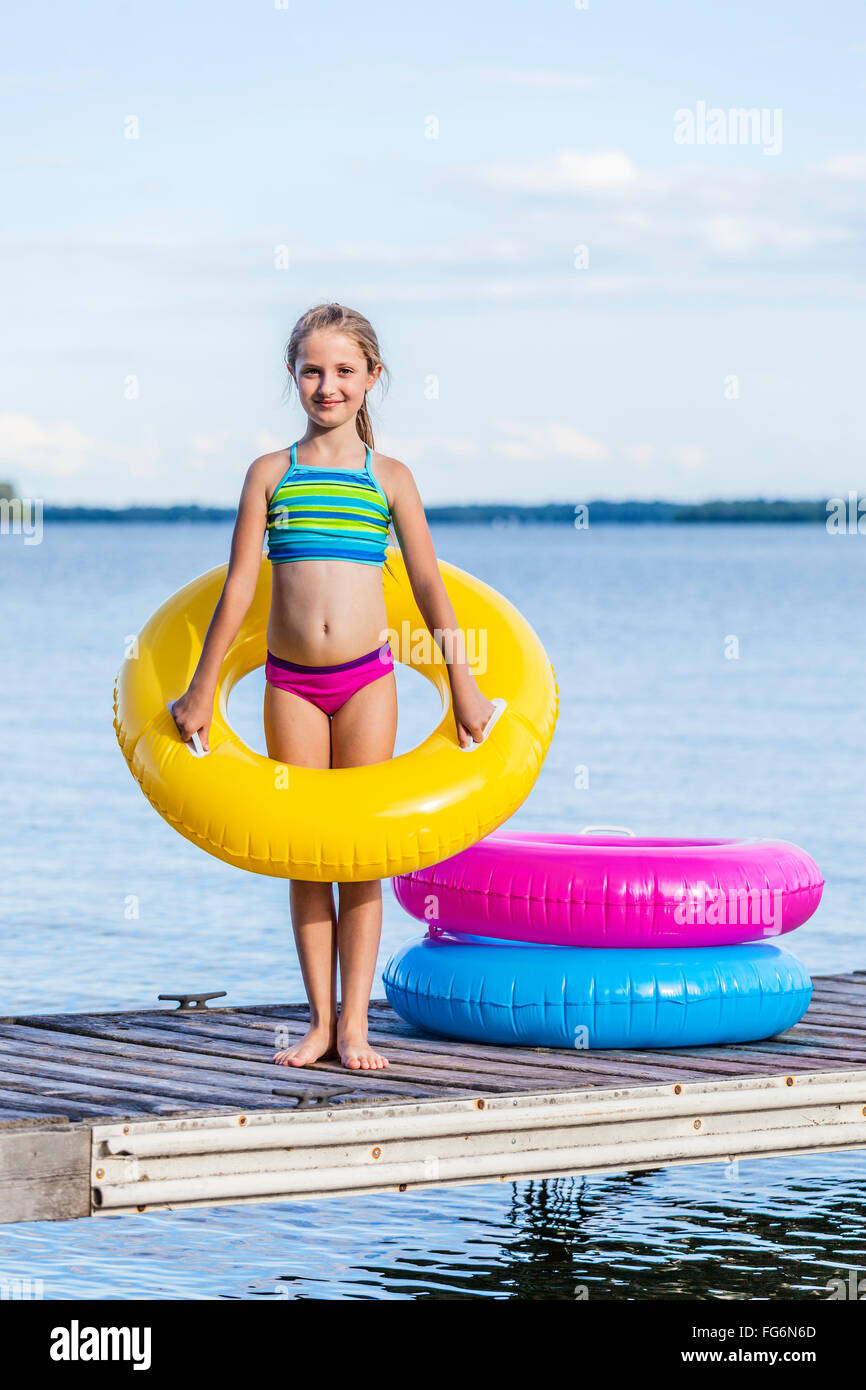 Mädchen am dock von Balsam Lake mit einem gelben aufblasbaren Ring; Ontario, Kanada Stockfoto