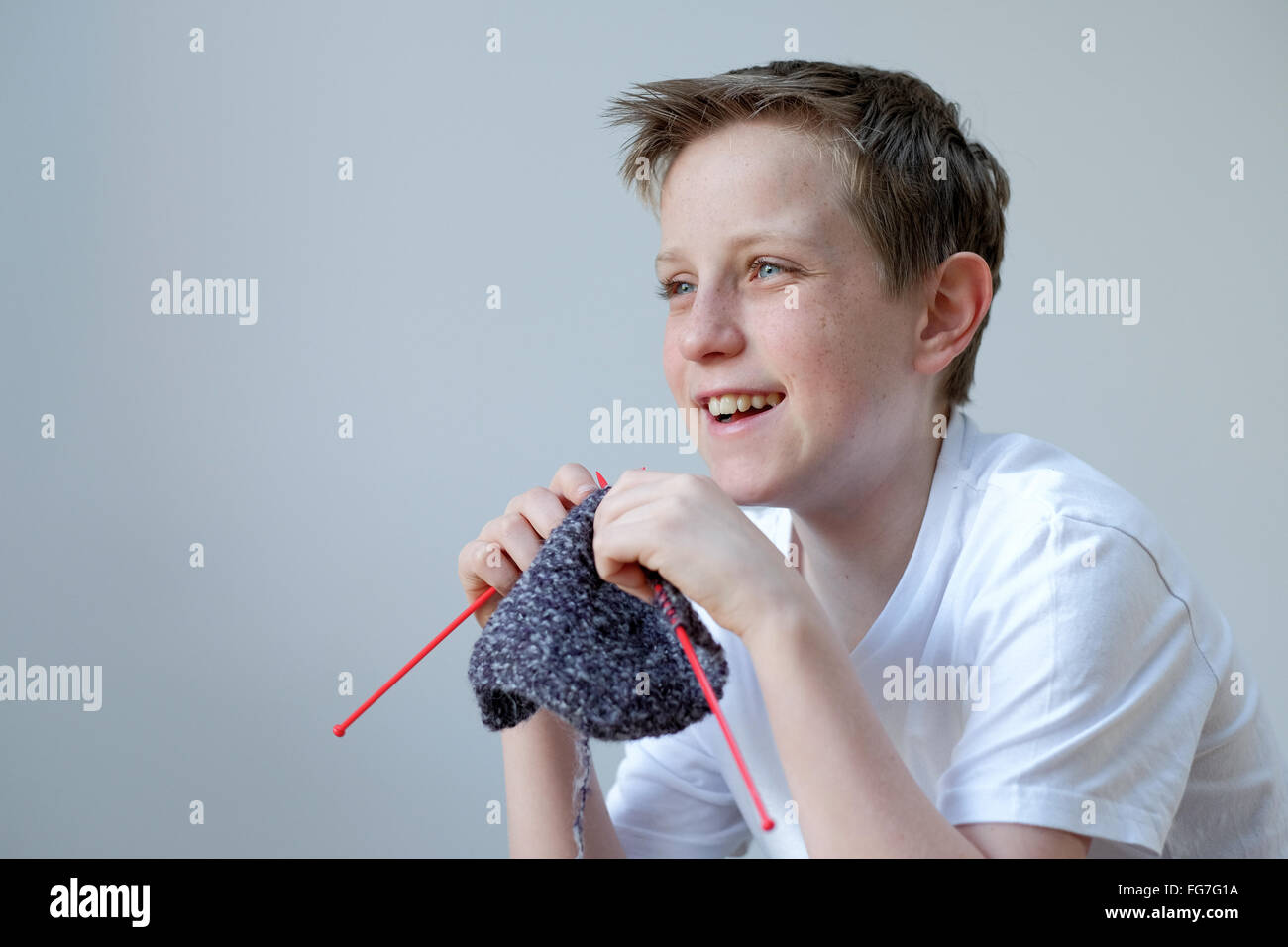 Ein fröhlicher Junge mit Wolle stricken Stockfoto