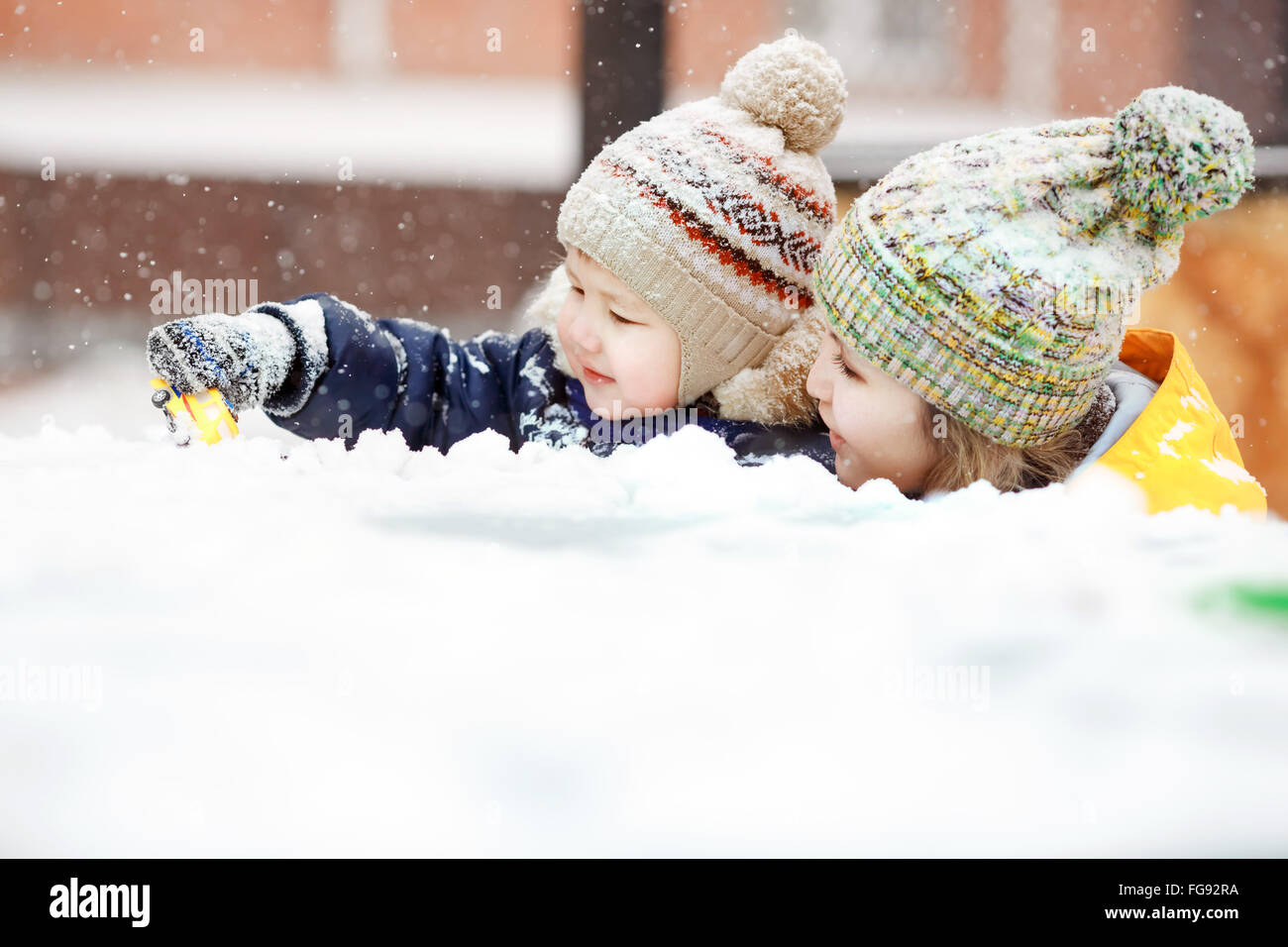 Mutter mit Kind spielen im Schnee auf Winterspaziergang, positive Emotionen, im Freien. Schneefall, Blizzard. Stockfoto