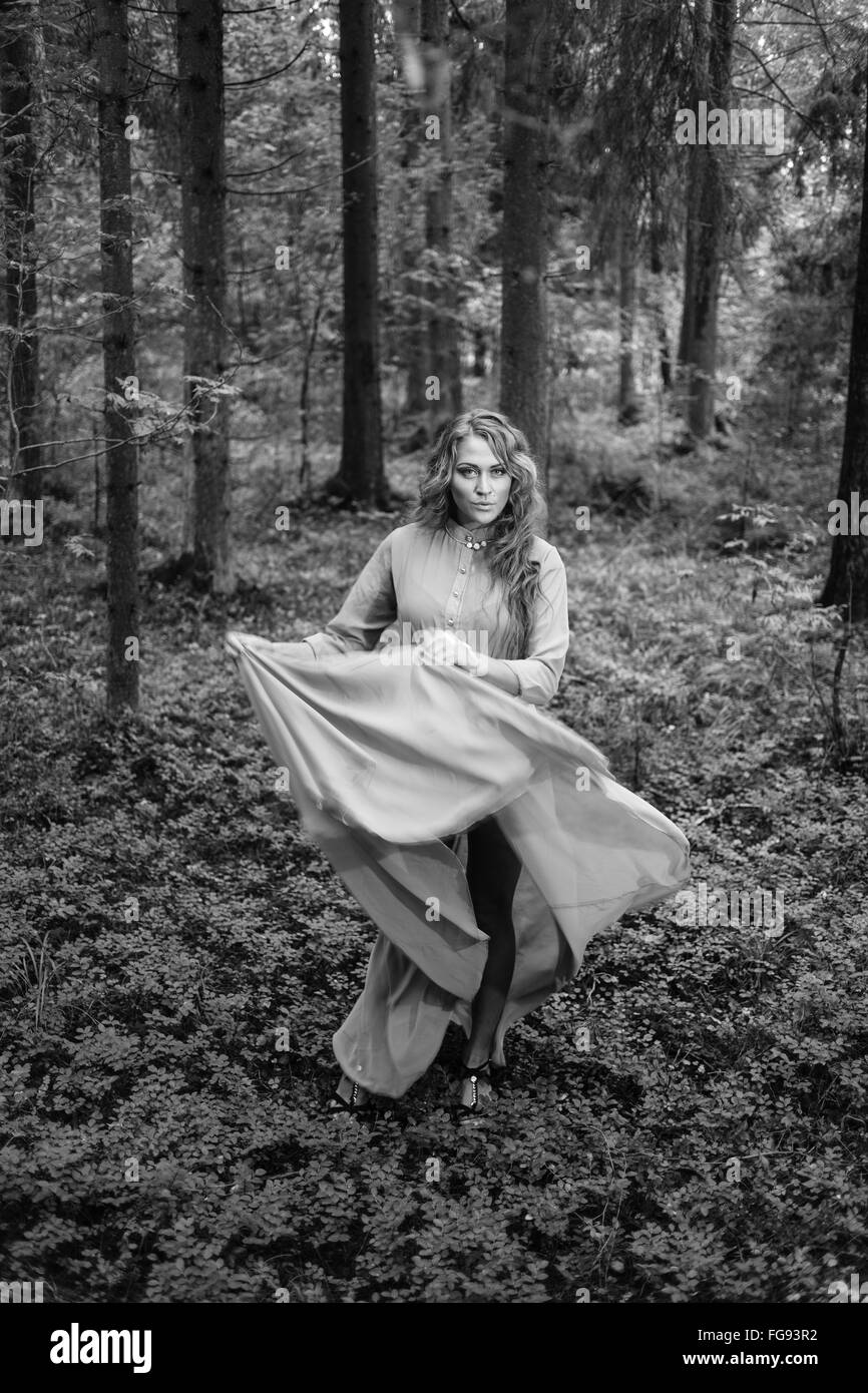 Langhaar-Mädchen im Kleid im Wald. BW Stockfoto