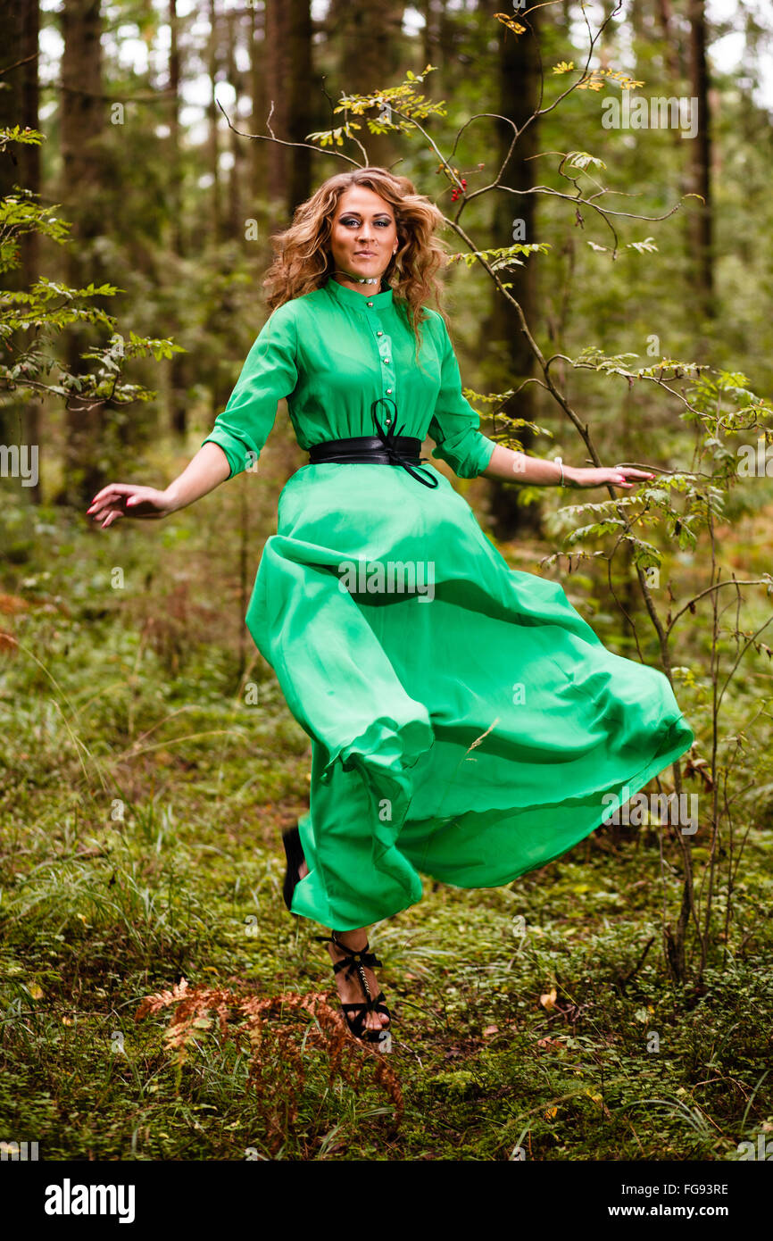 Fliegende Frau im langen Kleid im Wald. Stockfoto