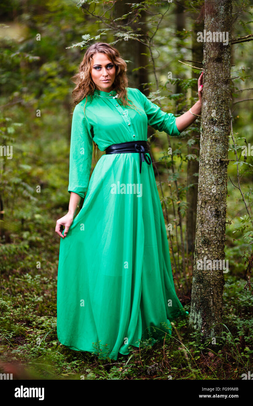 Langhaar-Mädchen im grünen Kleid im Wald. Stockfoto