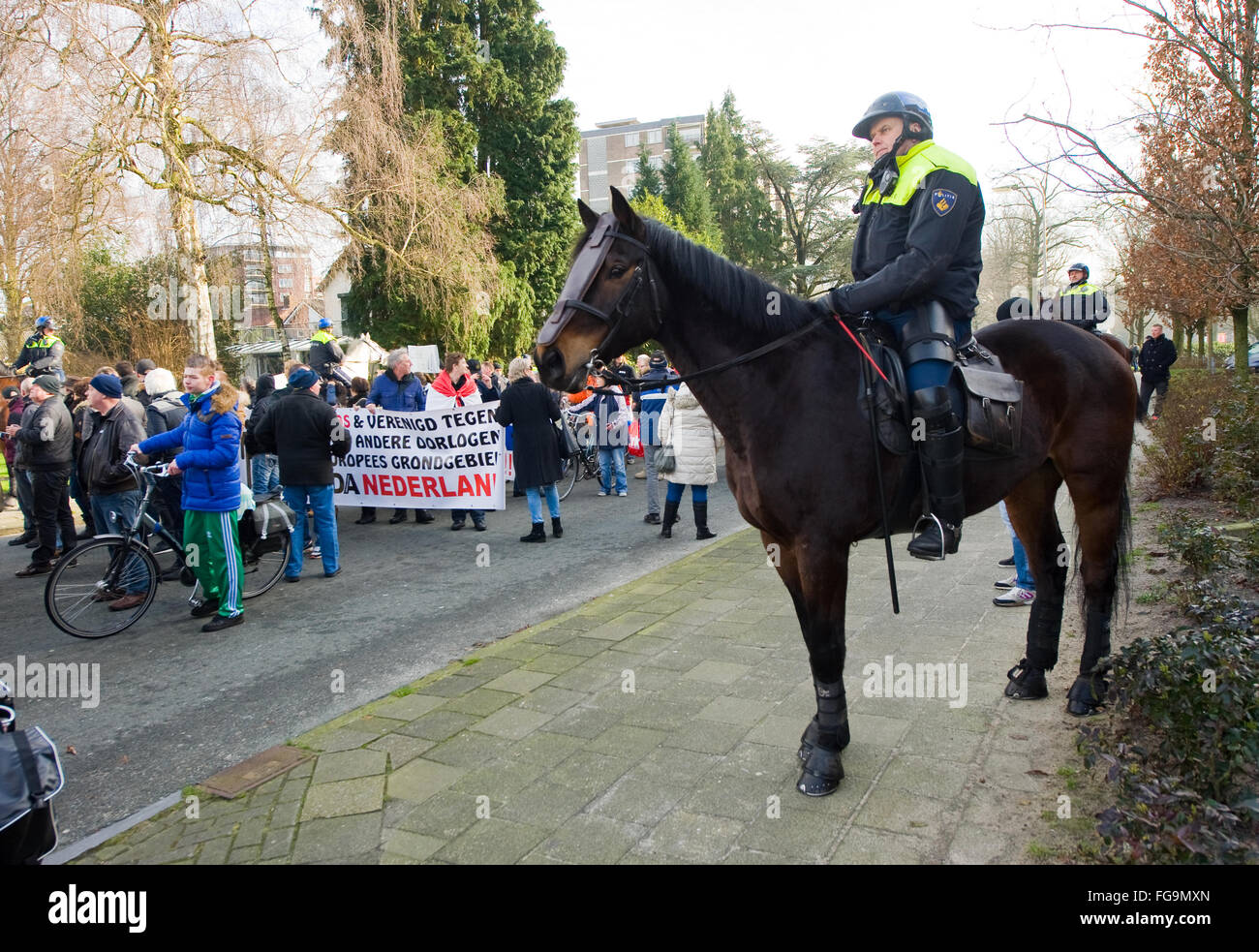 Ein Polizist auf einem Pferd beobachtet Menschen, die gegen eine riesige Migranten Lager für Flüchtlinge demonstrieren Stockfoto