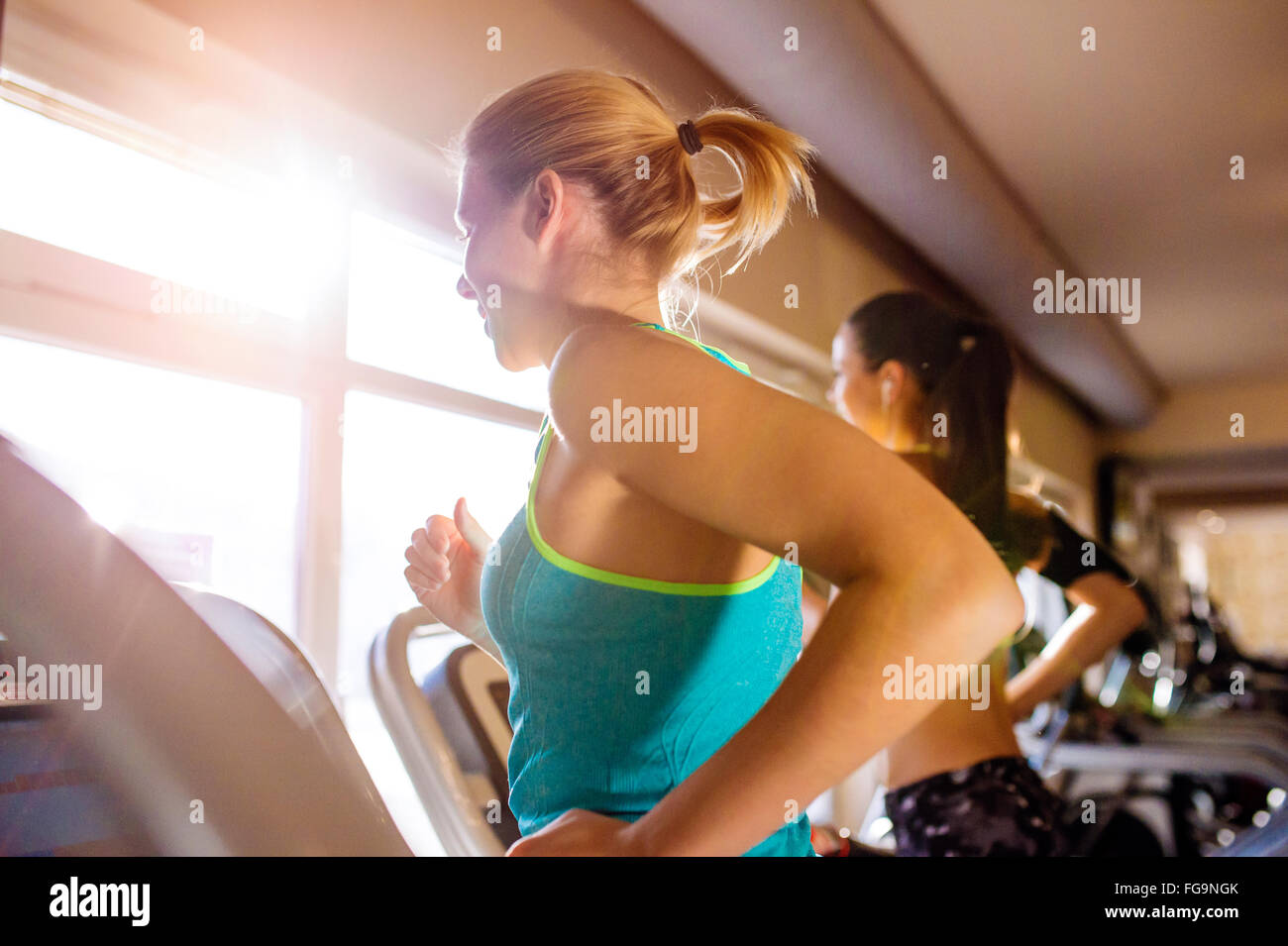 Zwei passen Frauen laufen auf Laufbändern im modernen Fitnessraum Stockfoto