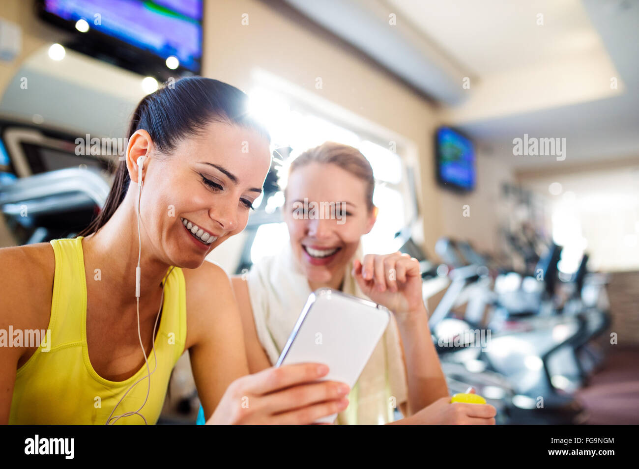 Passen zwei attraktive Frauen im Fitness-Studio mit Smartphone Stockfoto