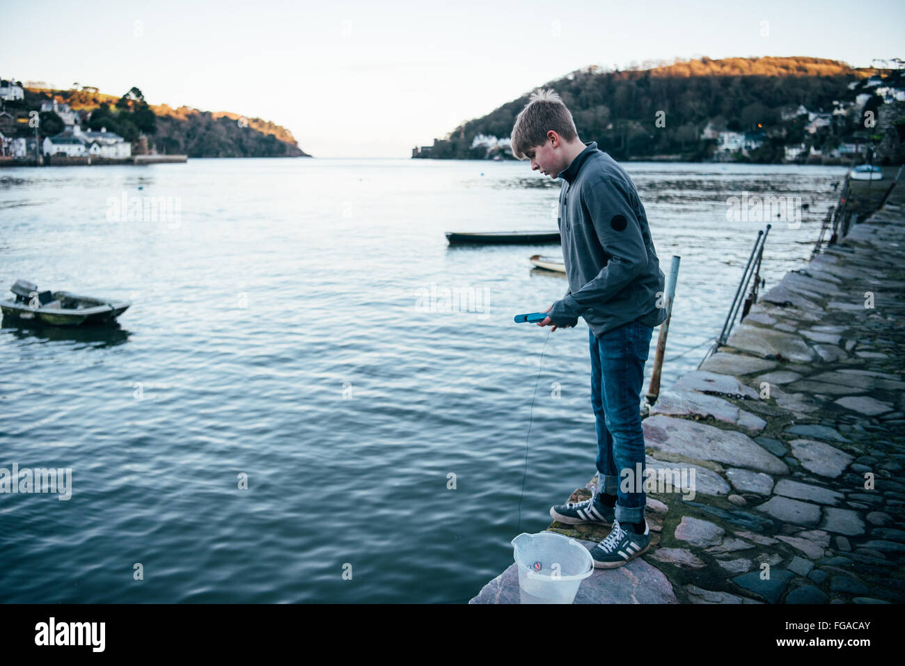 Teenager Verdrehungen in den Fluss Dart in der historischen Bayard Cove in Dartmouth Blick auf das Meer an einem Winterabend Stockfoto