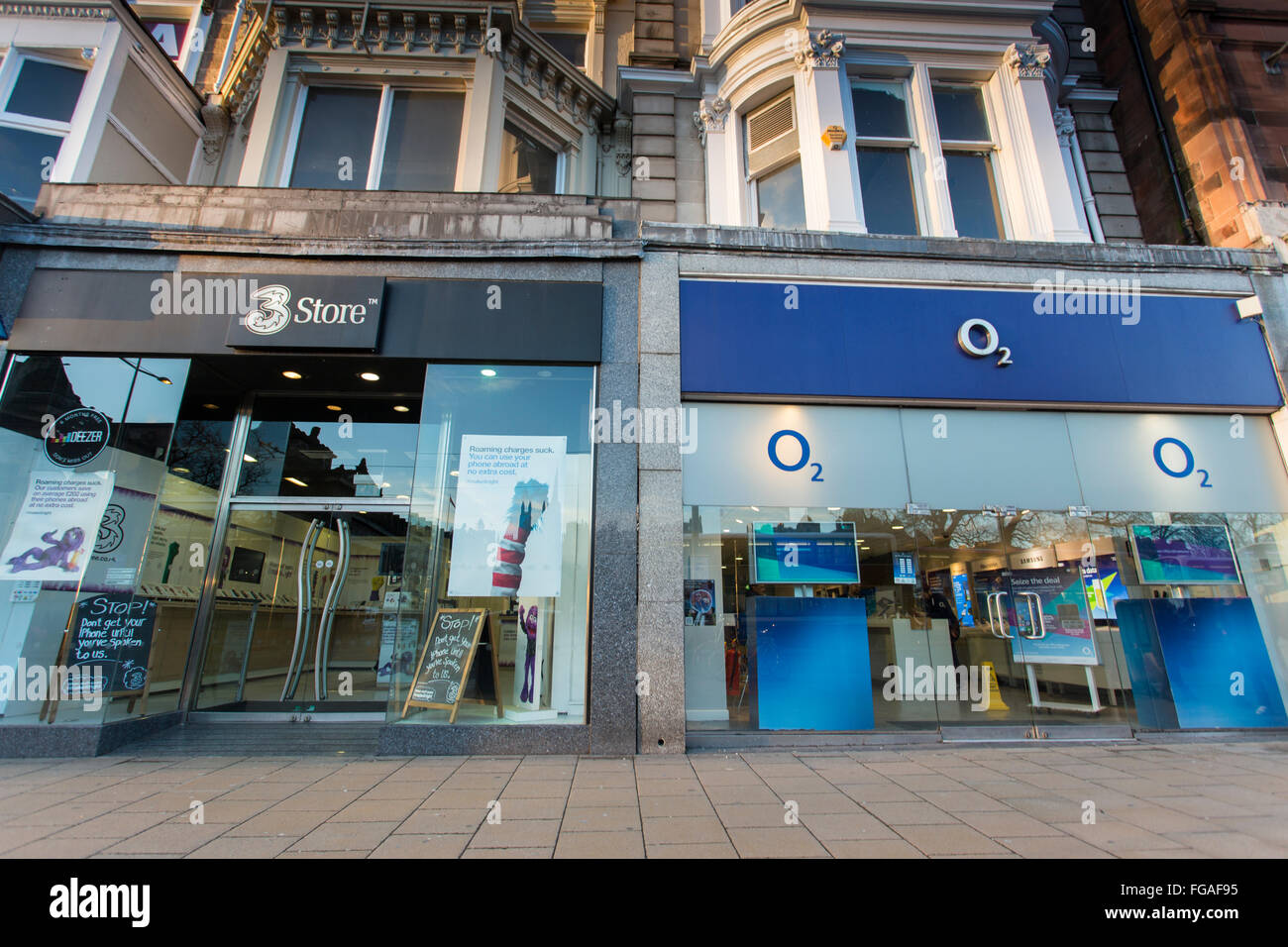Drei und O2 Shops in Edinburgh angrenzend. Drei Mobile will O2 mobile kaufen. Stockfoto
