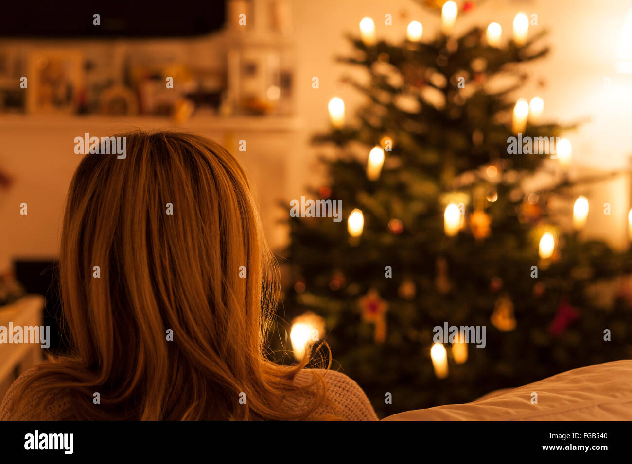 Frau sitzt auf dem Sofa mit Weihnachtsbaum Stockfoto