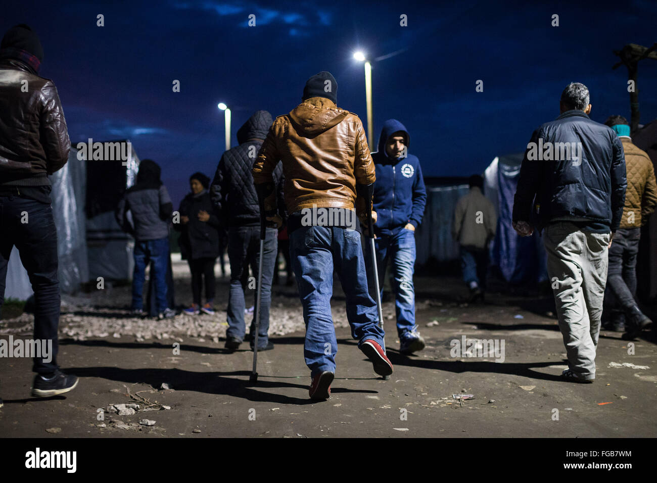 Ein Flüchtling auf Krücken bewegt sich durch den Dschungel Flüchtlingslager in Calais, Frankreich. Die Wege sind in der Nacht mehr los. Stockfoto