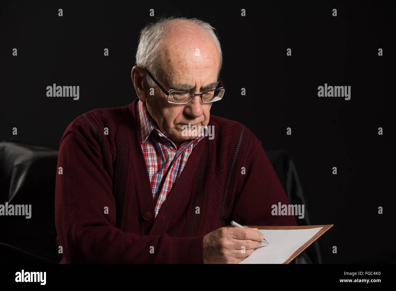 Alter Mann tragen Brillen schreiben einige Mitteilungen mit Pfanne und White paper Stockfoto