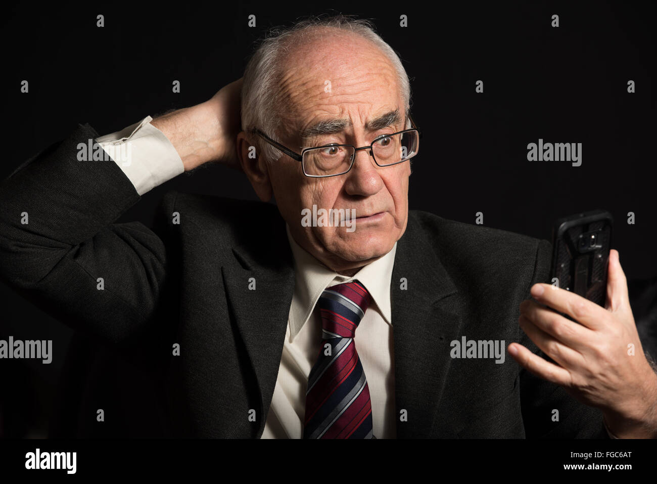 älteren Geschäftsmann, tragen Brillen auf schwarzem Hintergrund, Smartphone nutzt, hat video-chat Stockfoto