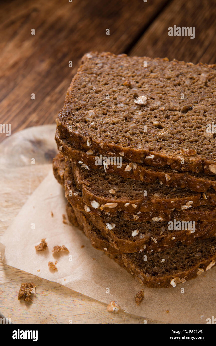 Schwarzbrot (in Scheiben geschnitten) auf einem alten Holztisch (Tiefenschärfe) Stockfoto