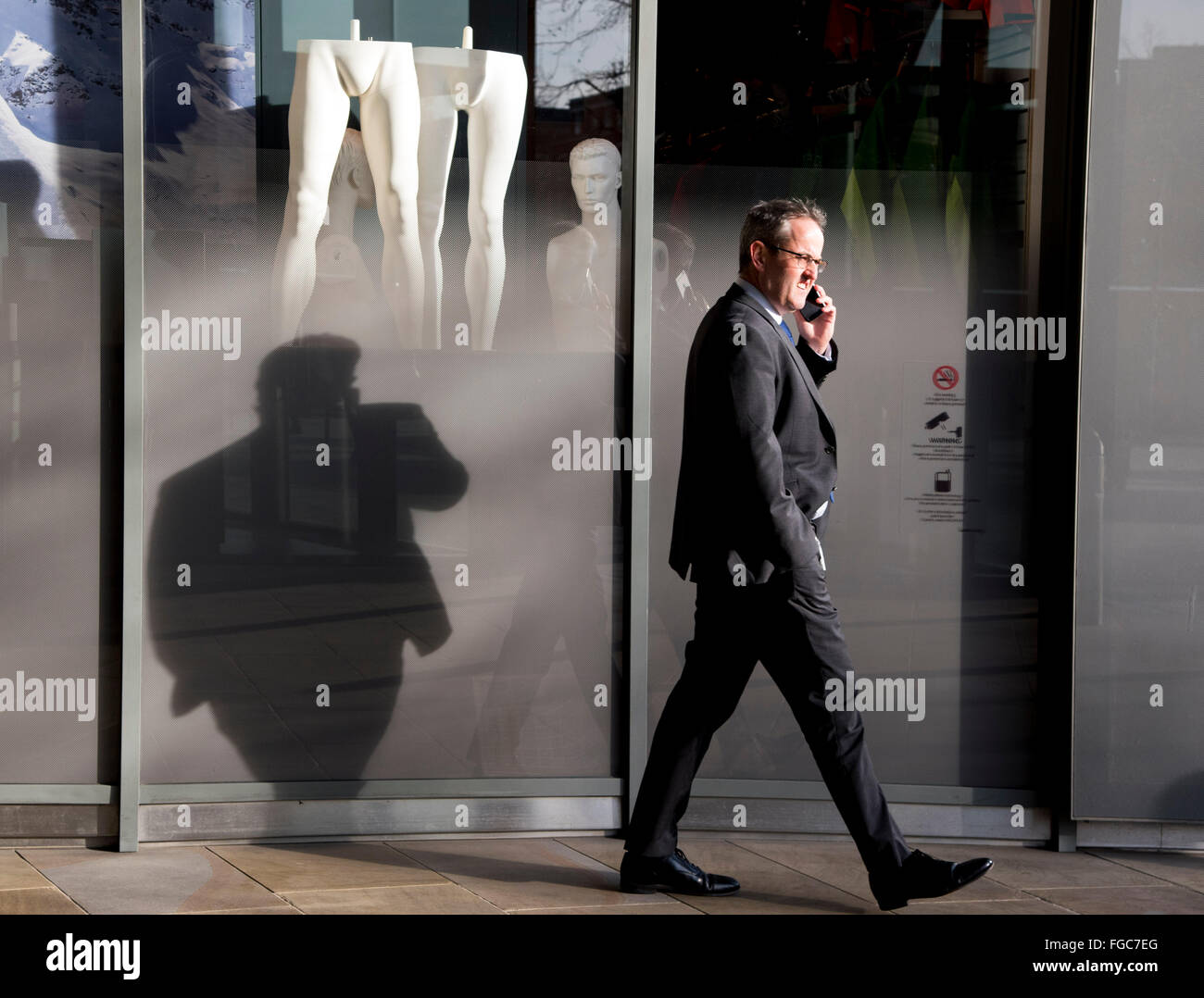 Mann am Telefon zu Fuß vorbei an männliche Schaufensterpuppe geeignet Stockfoto