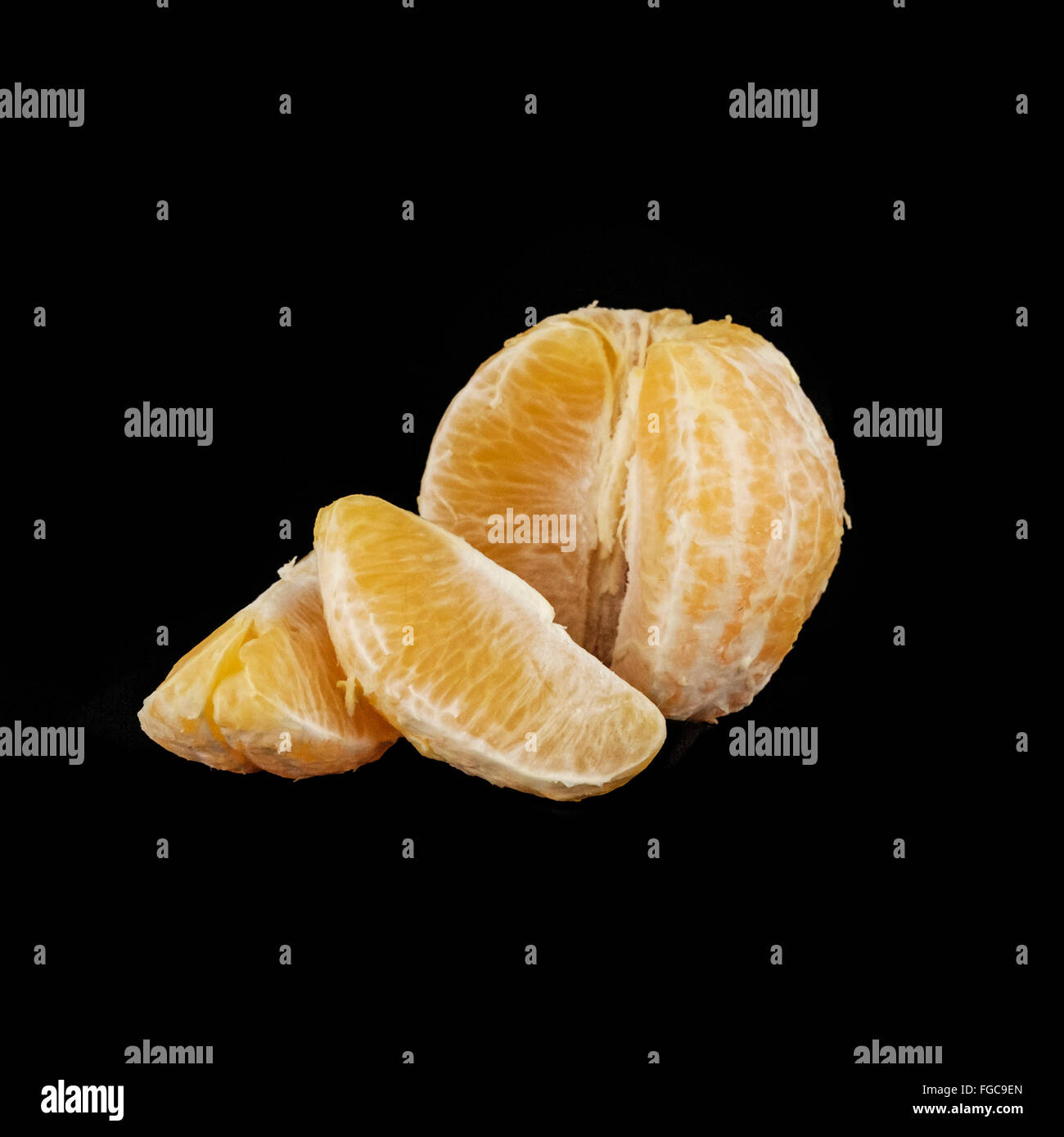 Eine geschälte Orange citrus x Sinensis, auf einem schwarzen Hintergrund in Abschnitte, gebrochen. Stockfoto