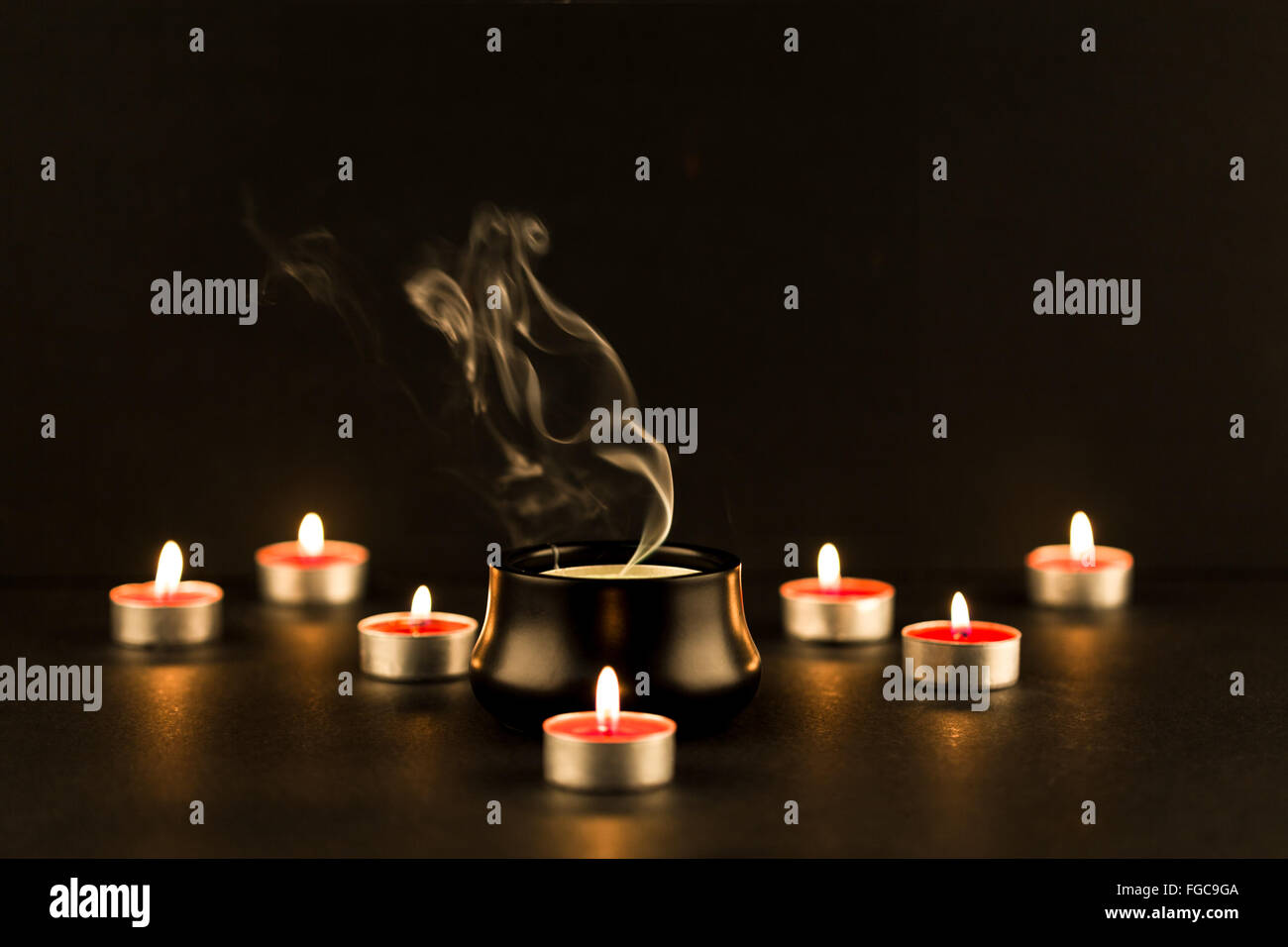 Gruppe von brennenden Kerzen und eine große Kerze erlischt in der Mitte mit  komplizierten Rauch Geplapper steigt Stockfotografie - Alamy