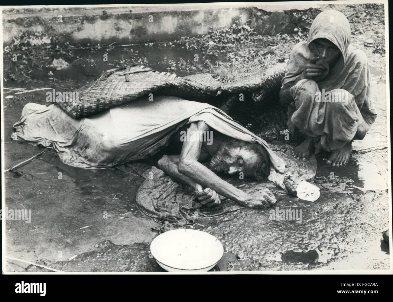 1955 - ein altes mittellos aus Bangladesch starb in der Nähe von Bahnhof Bangaon nach einer langen Reise von Faridpur. Die Leiche liegt stundenlang zu sammeln unter Regen und Wasser auf ein offener Ort. Seine Frau ist neben. © Keystone Bilder USA/ZUMAPRESS.com/Alamy Live-Nachrichten Stockfoto