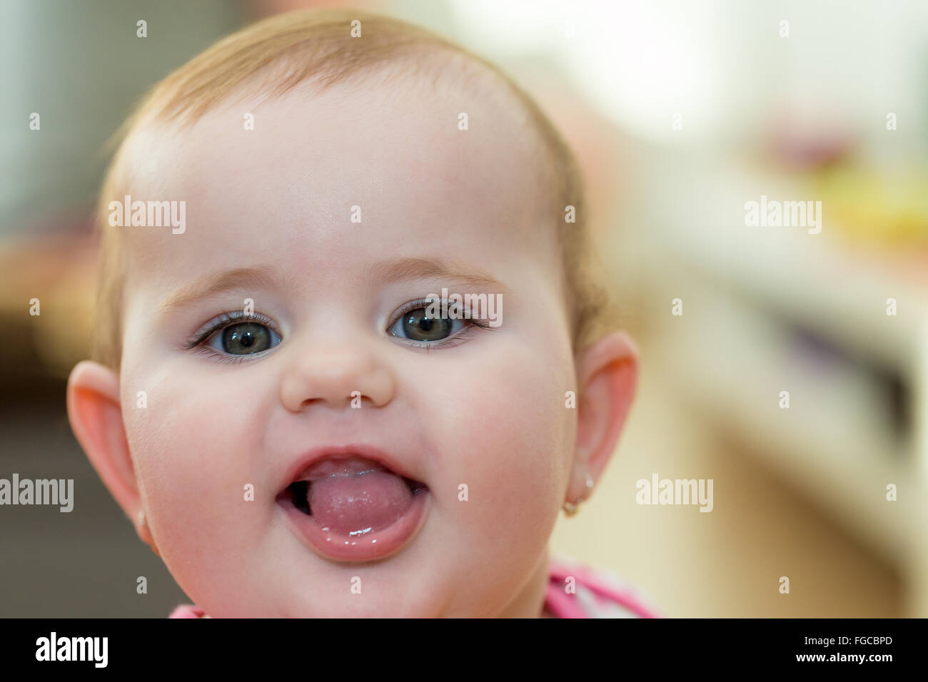 Glückliches niedliche kleine einjähriges Mädchen innen Lächeln auf den Lippen und Zunge kleben Stockfoto