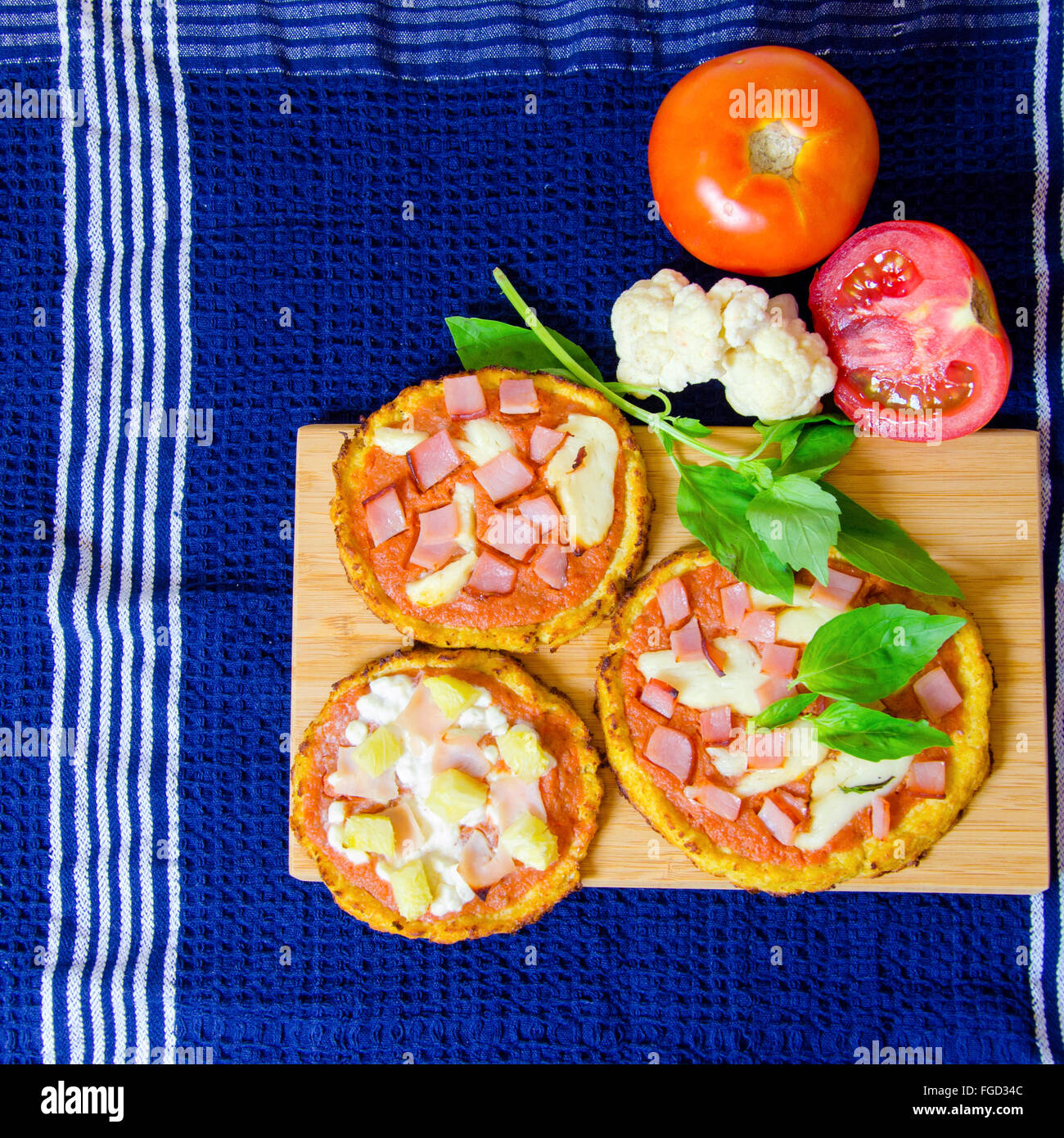 Draufsicht der drei kleine Runde gebackene Pizzen aus Blumenkohl Kruste und garniert mit Speck, Schinken, Halloumi-Käse, Hüttenkäse Stockfoto