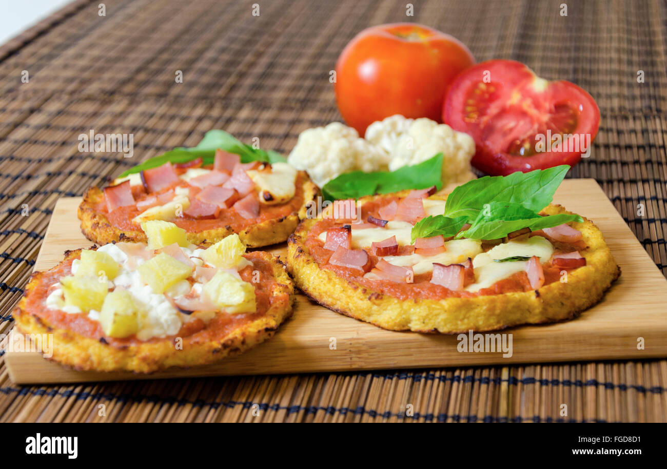 Drei kleine Runde gebackene Pizzen aus Blumenkohl Kruste und garniert mit Speck, Schinken, Halloumi-Käse, Hüttenkäse, Lountza, p Stockfoto