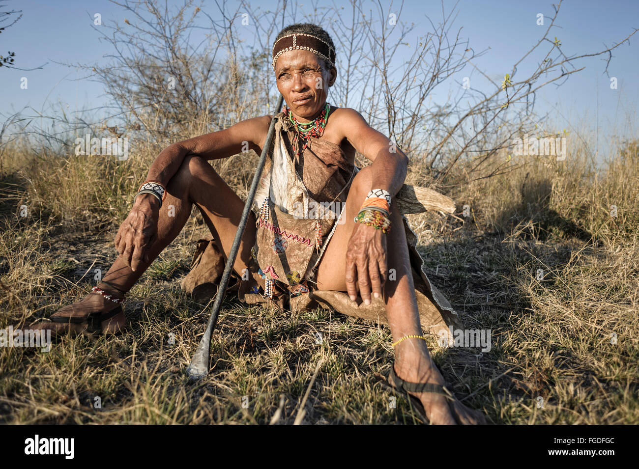 Porträt einer Buschmänner Frau sitzt auf dem Boden der Kalahari-Wüste bei Sonnenuntergang. Stockfoto