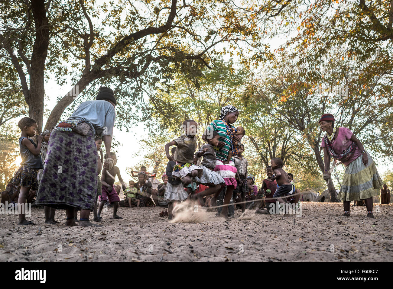 Frauen und Kinder des Stammes San in der Kalahari-Wüste spielen, um das Seil vor Sonnenuntergang zu springen. Stockfoto