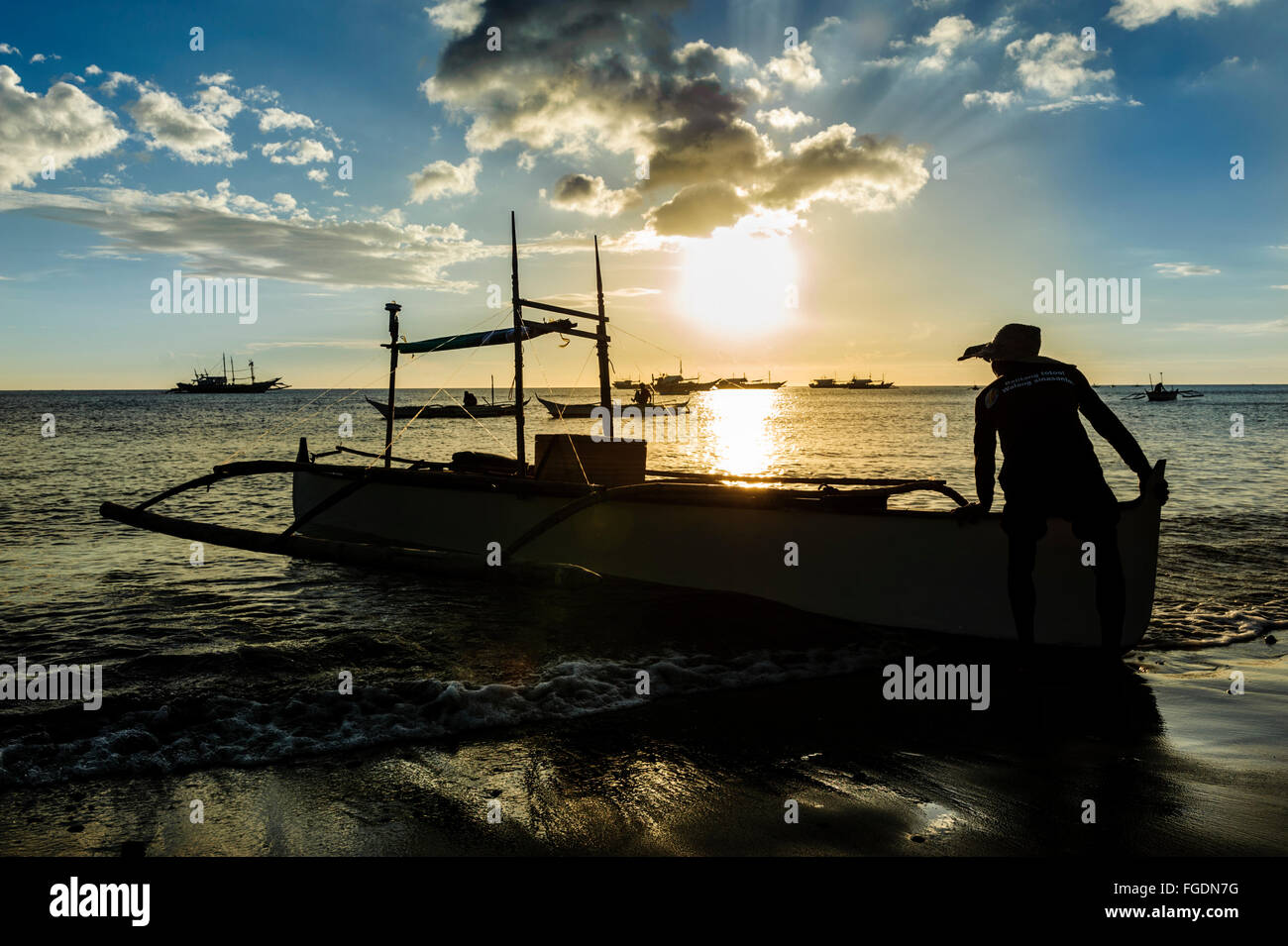 Fischer, die das Boot auf das Meer zum Angeln bei Sonnenuntergang herausschieben. Stockfoto