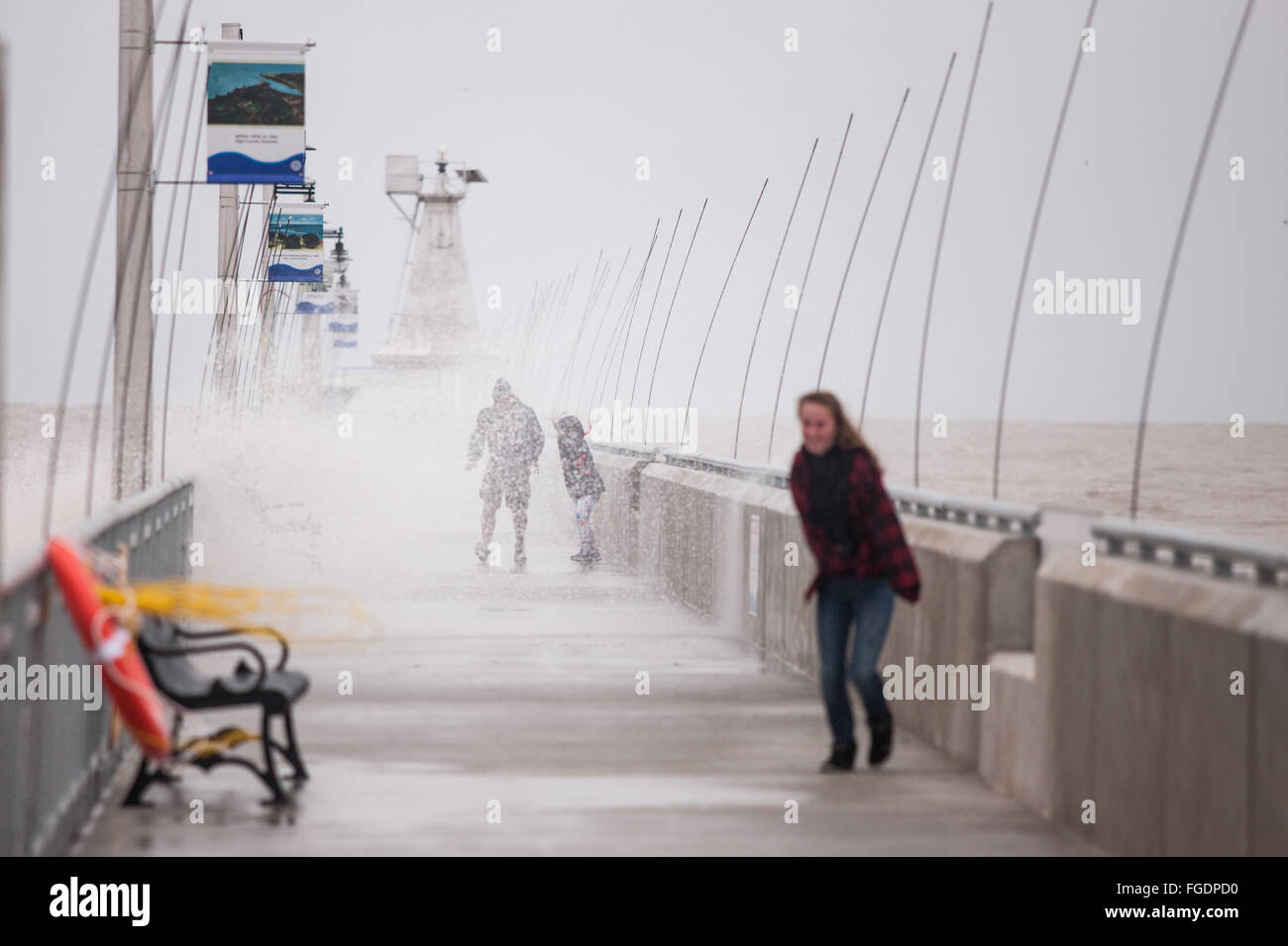 Port Stanley, Kanada - Oktober 3,2015. Wellen Absturz über die öffentlichen Pier in Port Stanley, wie eine Familie versucht, trocken zu bleiben. Stockfoto