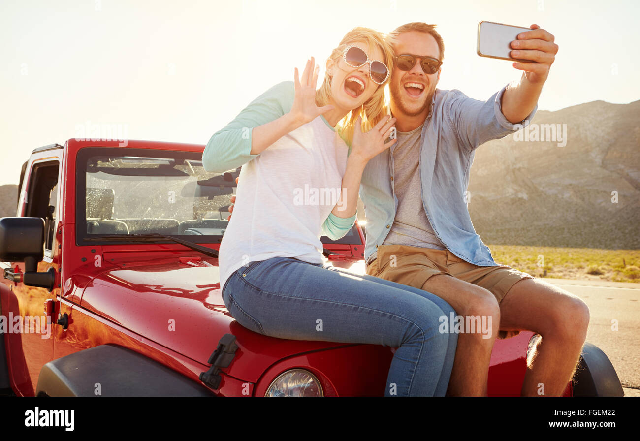 Paar auf Roadtrip sitzen auf Cabrio nehmen Selfie Stockfoto