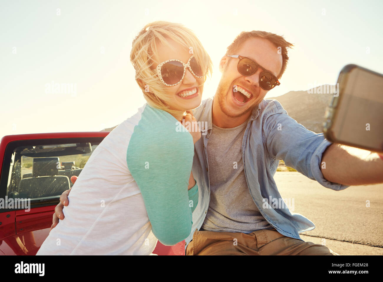Paar auf Roadtrip sitzen auf Cabrio nehmen Selfie Stockfoto